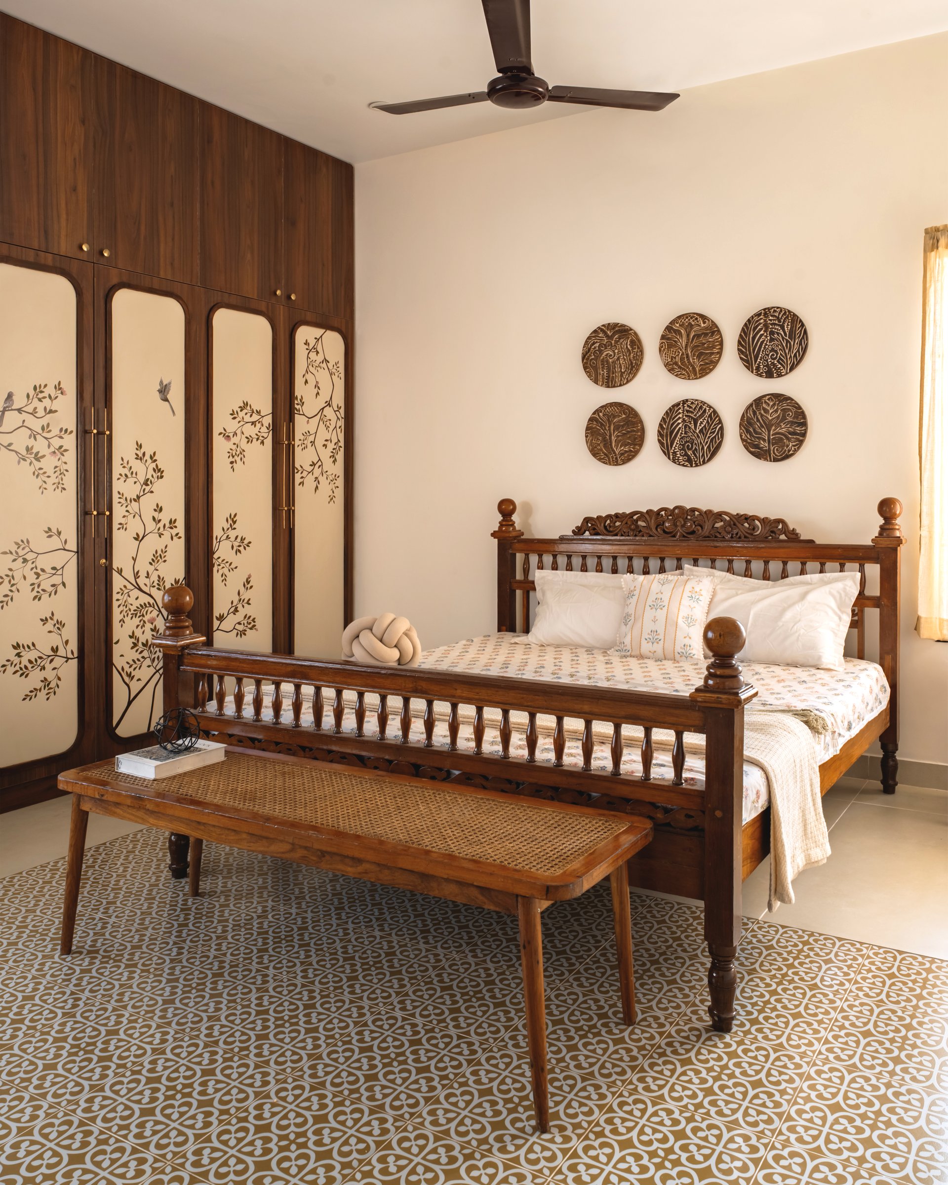 The bedroom seen from the other side: plain cream walls, sheer curtains, and the painted wardrobe as the only ornament