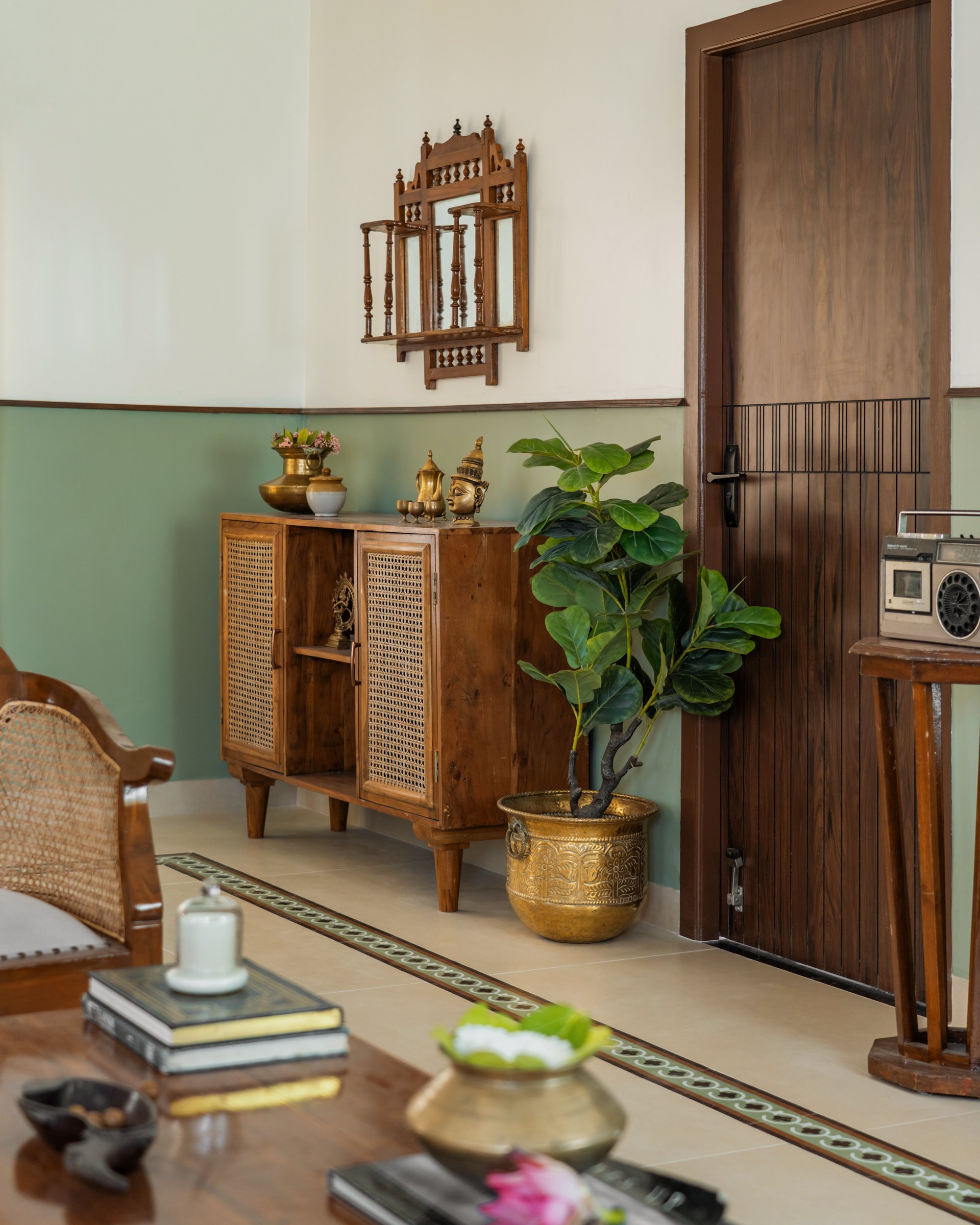 The same corner read closer, where a fiddle-leaf in a brass planter meets a panelled wooden door