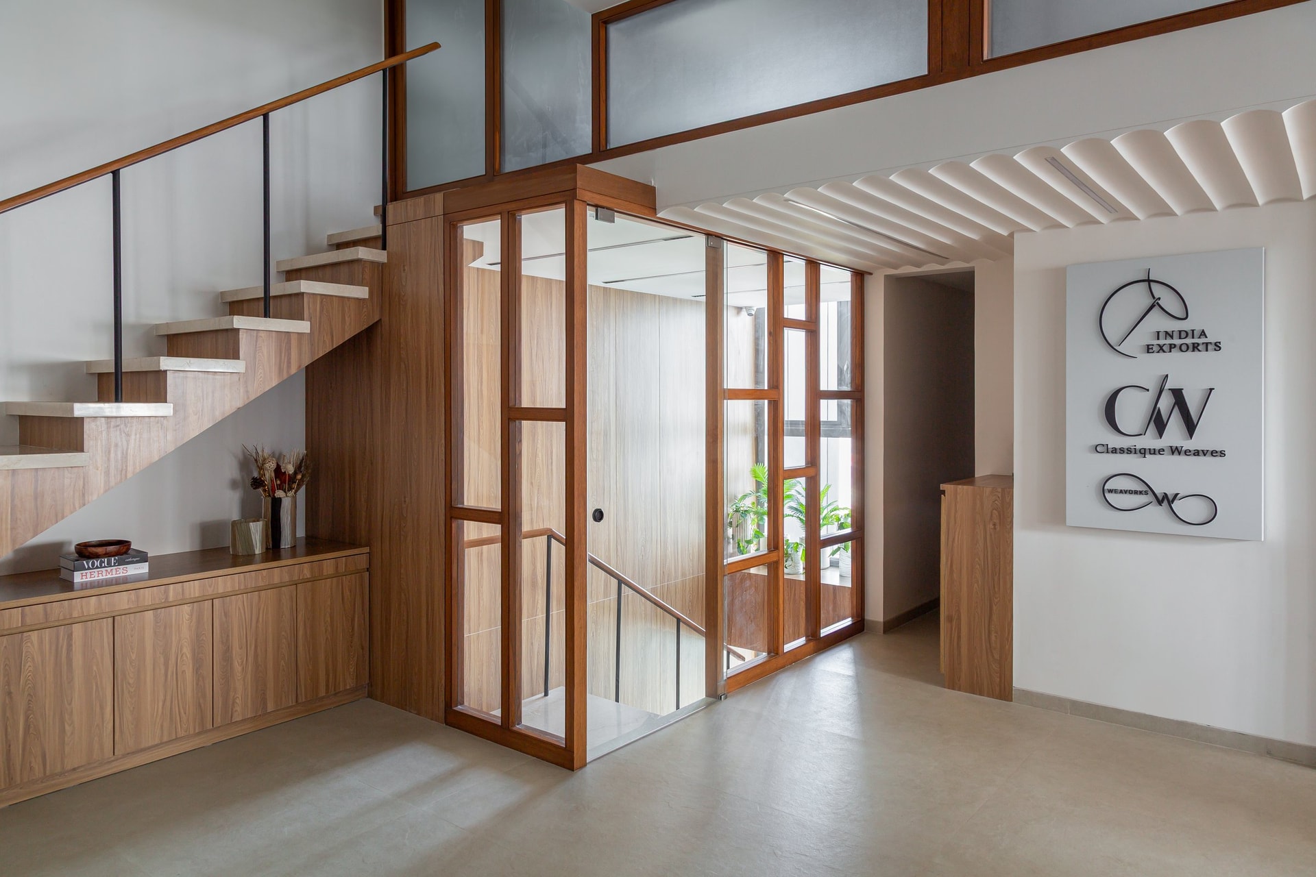 The arrival level, where a wood-framed enclosure houses the internal staircase between floors and a signage wall introduces the brand identity