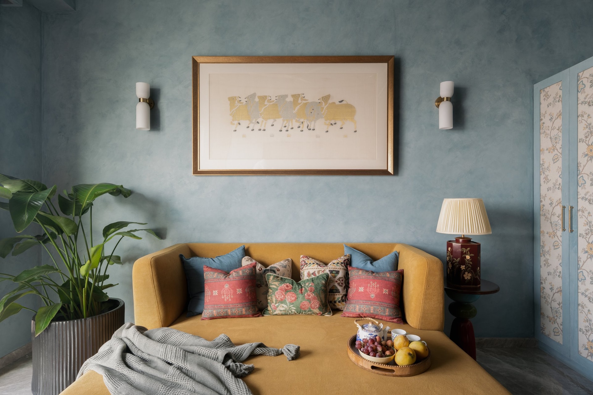 The study and television room: a mustard daybed against limewashed blue walls, the home's quietest composition