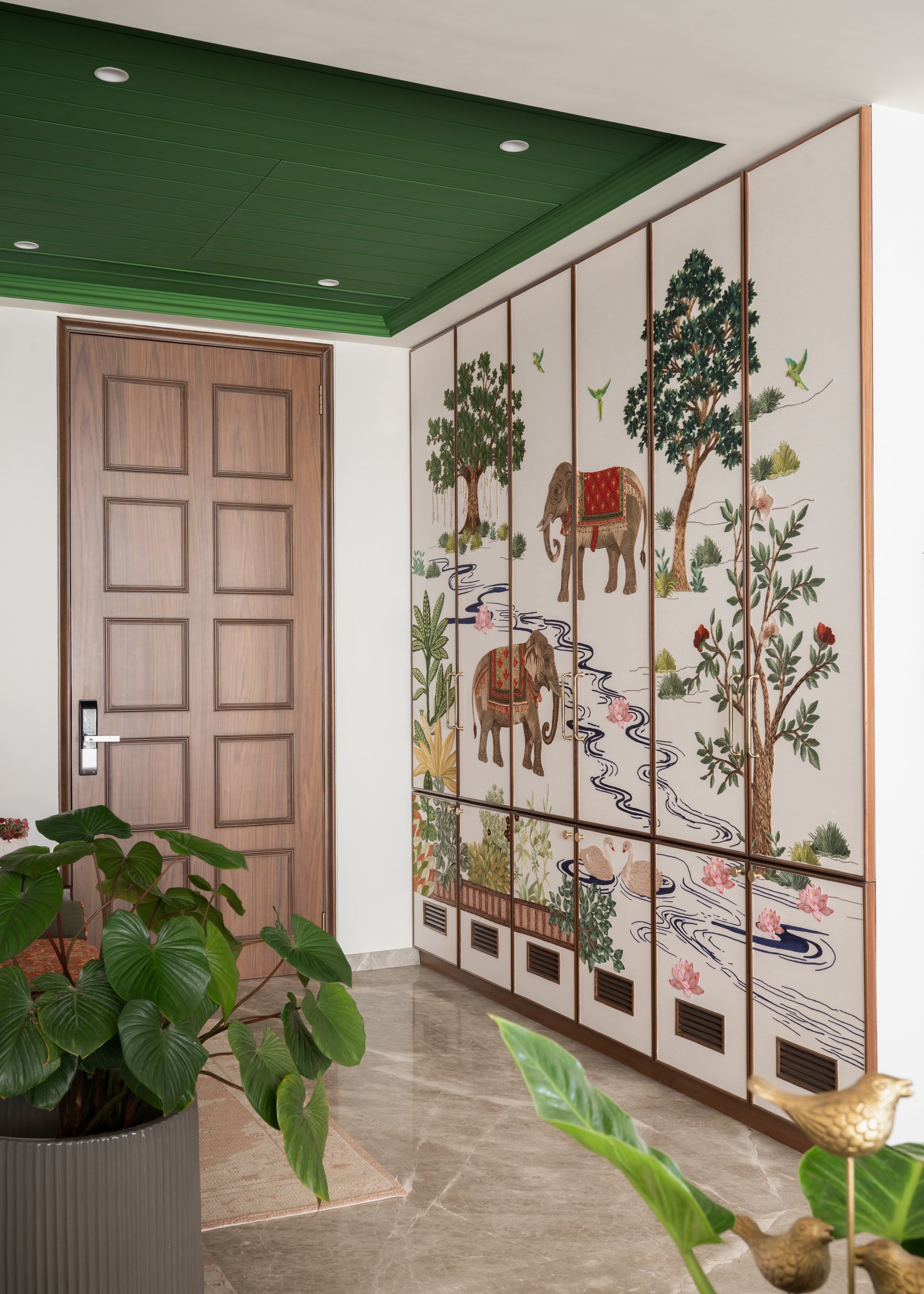 The foyer: a green-painted slatted ceiling above a tall run of hand-embroidered cabinetry sets the home's tone before the door is even opened