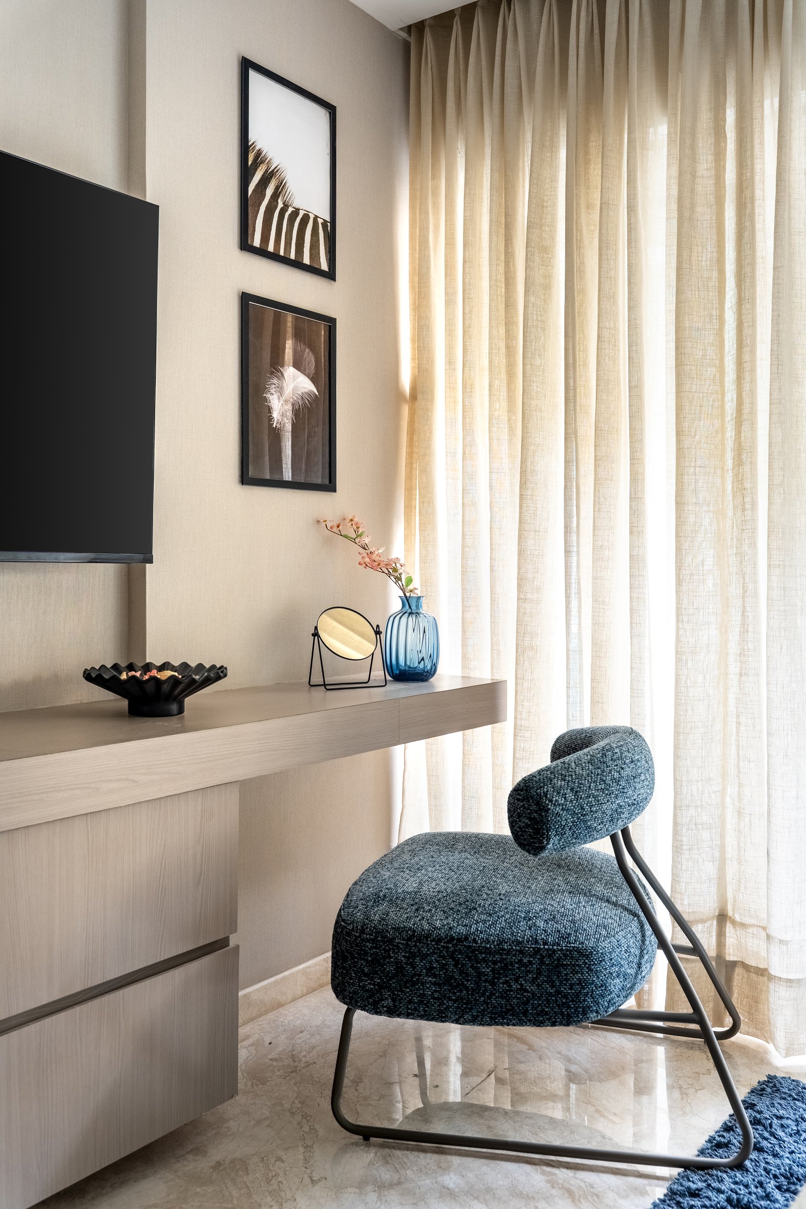 A dressing corner within the same room, where a blue bouclé chair and pale ash console make a room of a transition