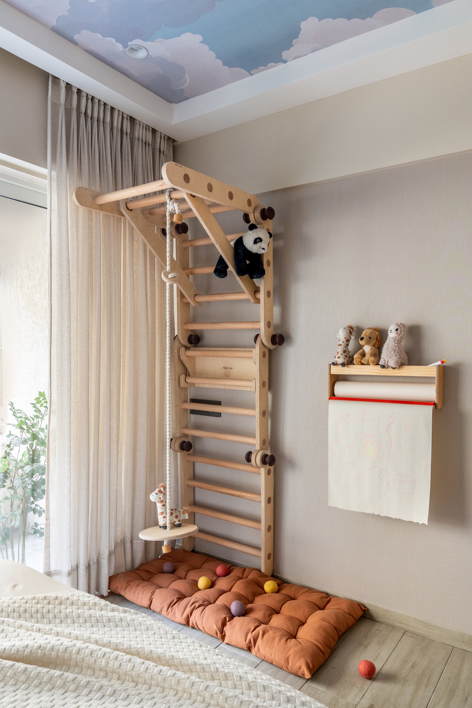 A pale-wood indoor climbing frame turns the bedroom into something closer to a small world