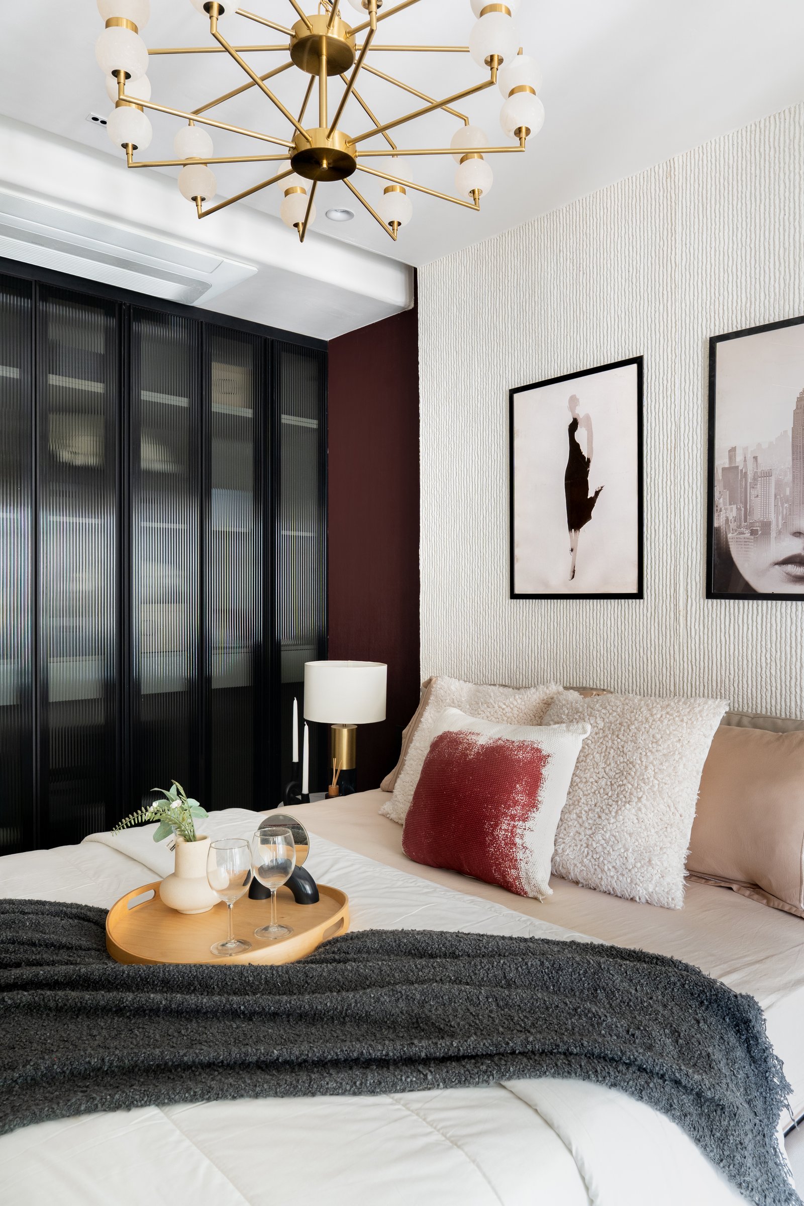 A secondary bedroom, where a deep oxblood accent wall and textured cream relief create a more graphic register