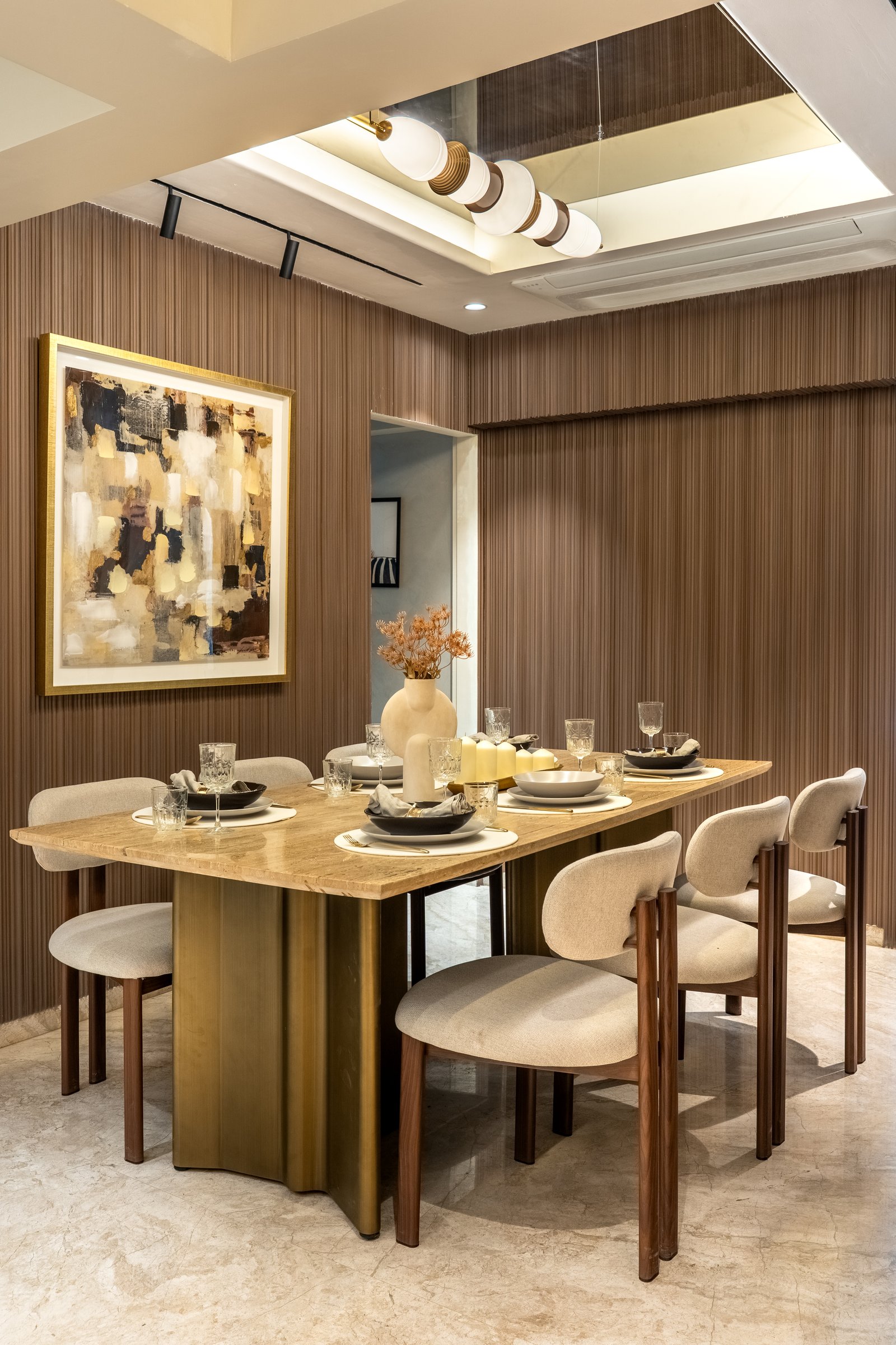 The dining room, where reeded wood panelling and a brushed-brass table base anchor a more enveloping register