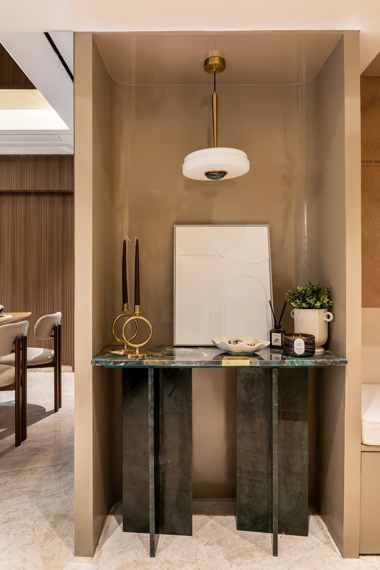 The entry, where a green marble console and a recessed taupe alcove establish the home's material grammar