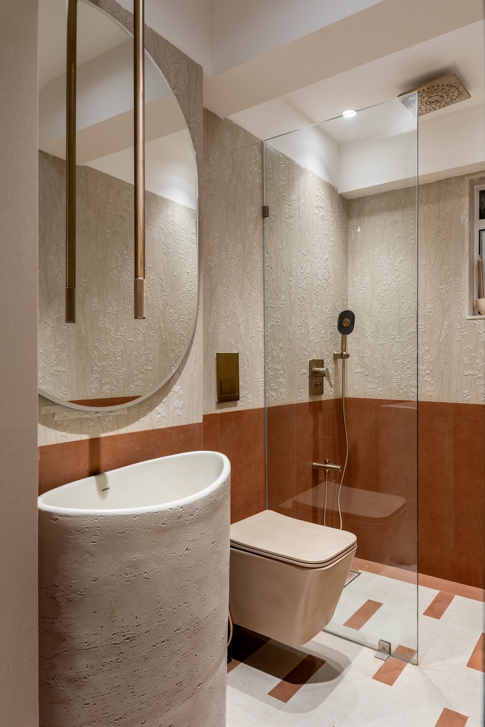 A second bathroom, where a textured floral relief in pale plaster meets warm terracotta tile in a more crafted register