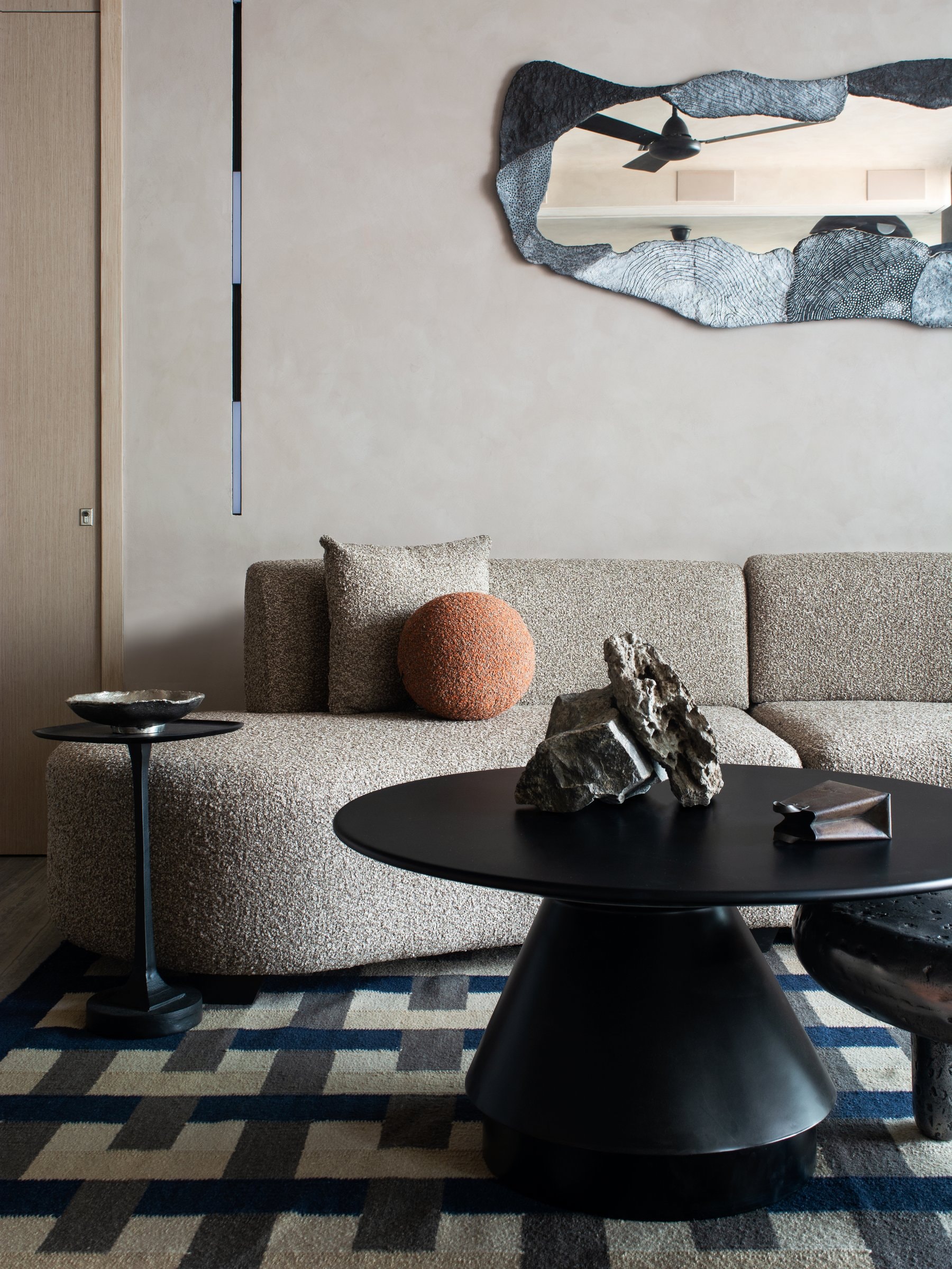 A closer view of the seating: the sculpted mirror frame in conversation with raw mineral specimens on the black pedestal table