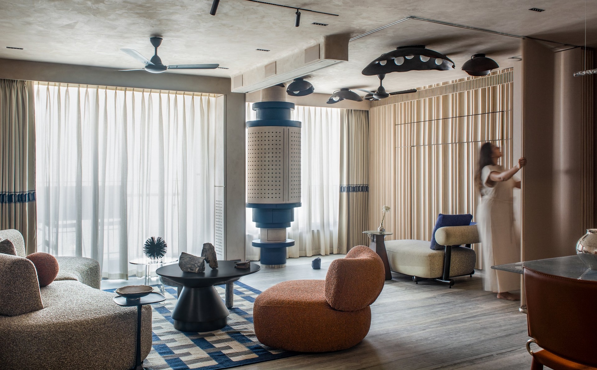 The living room, where a perforated cylindrical column rises as sculpture and a reeded screen wall slides open along one edge