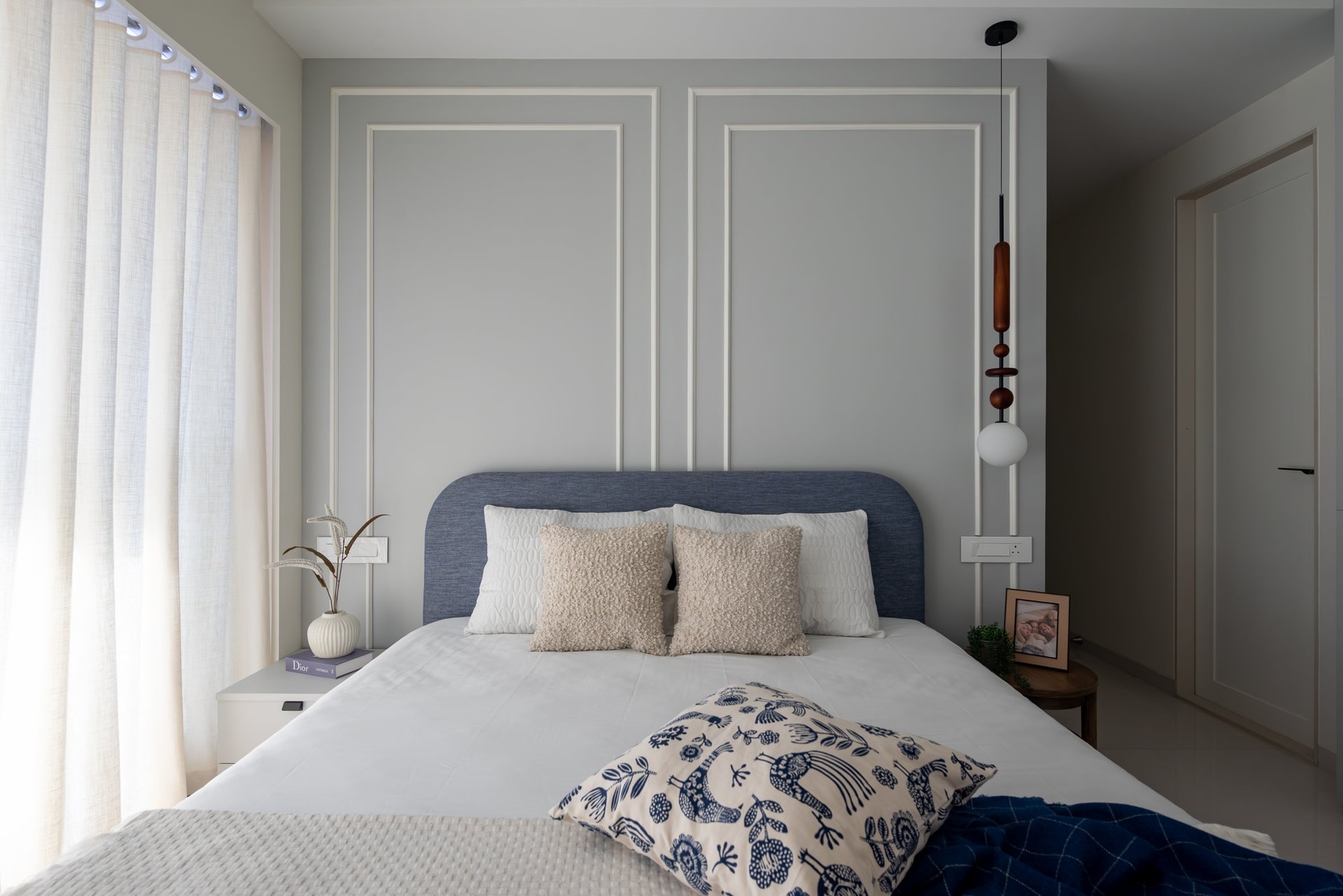 Another bedroom shifts toward cool greys, with a sculptural beaded pendant beside the bed