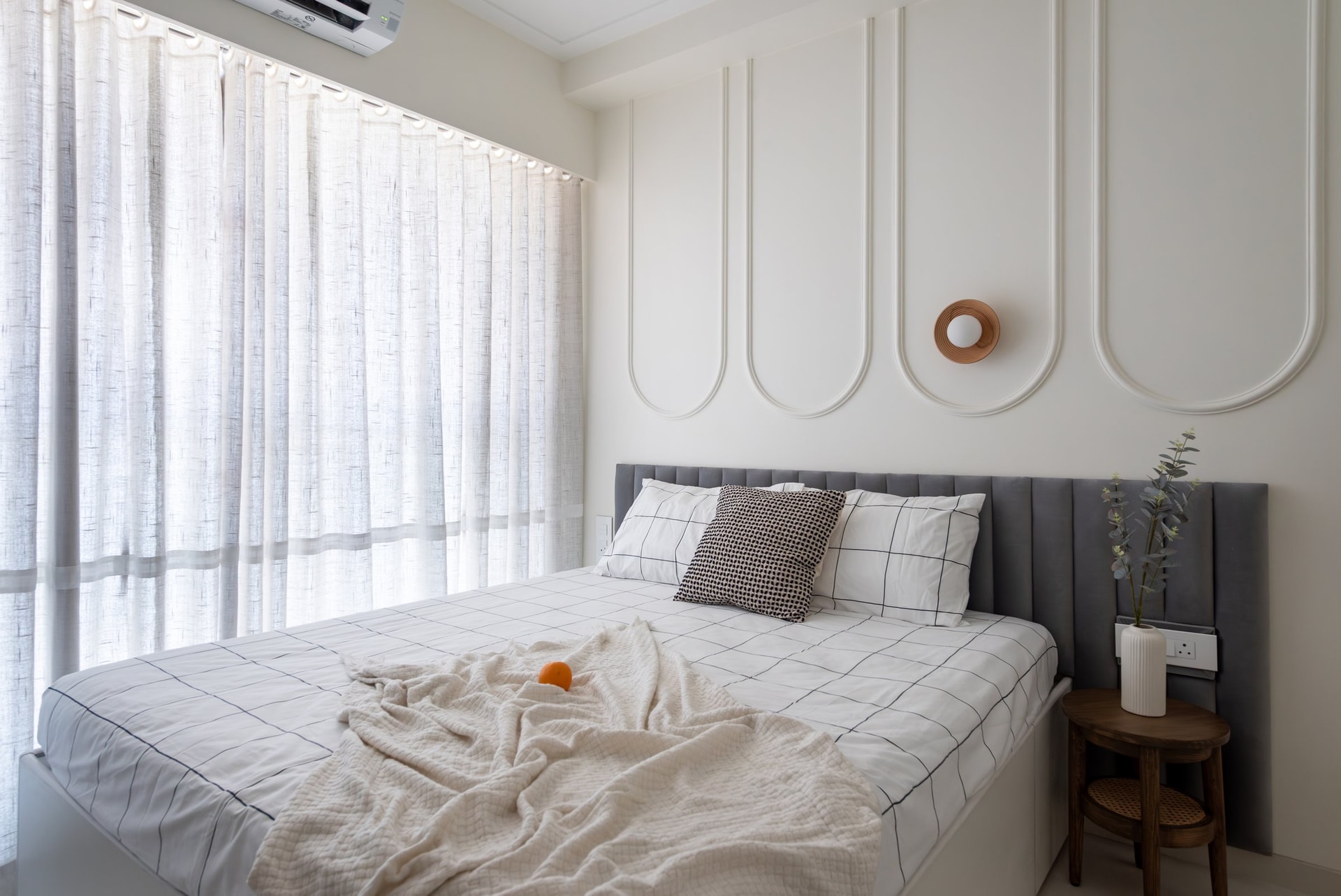 A second bedroom, where classical arched mouldings sit behind a grey channelled headboard