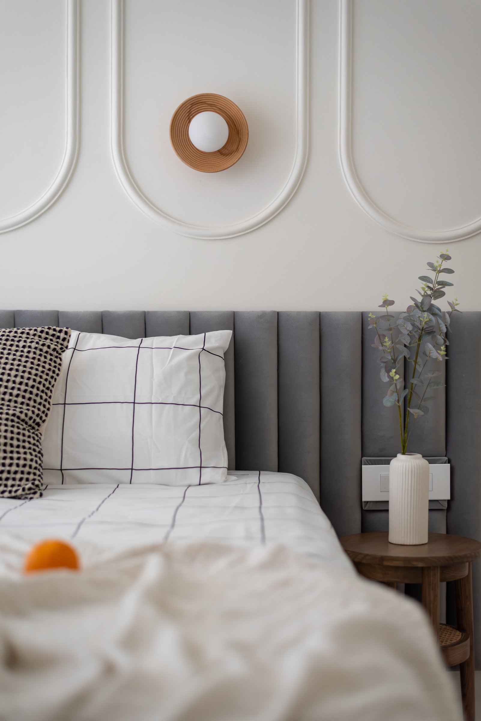 A small wood-and-glass sconce becomes the room's most considered detail