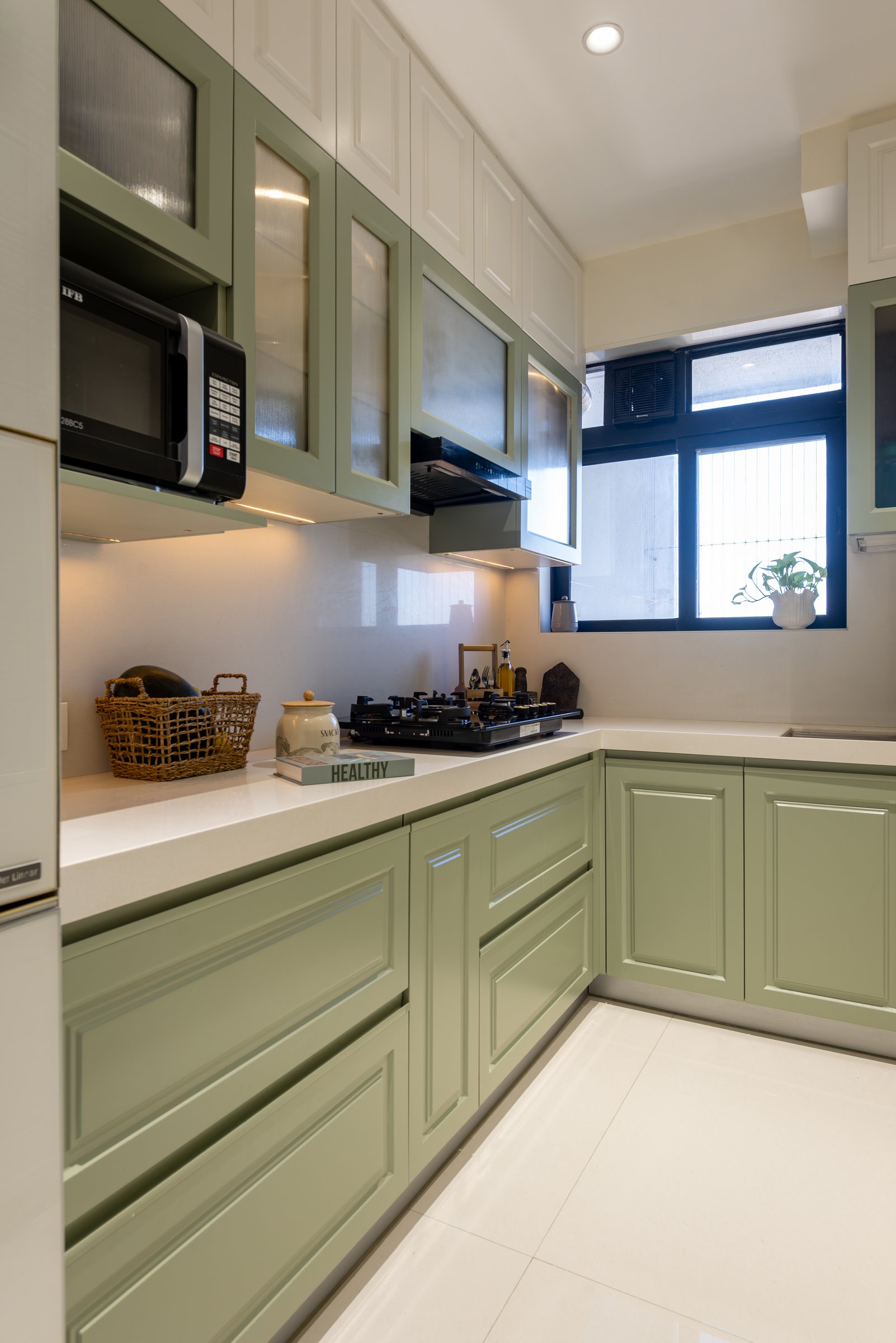 The kitchen, where sage-green cabinetry grants one utility-driven space its own distinct character
