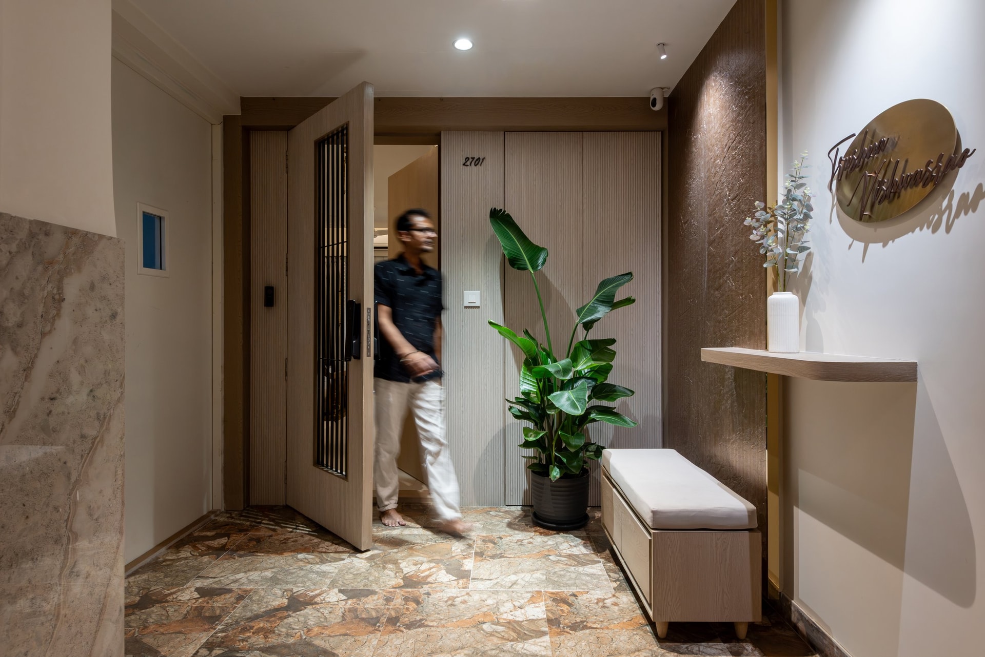 The entry, where a reeded wood-panelled wall and patterned stone floor establish the home's tonal overture