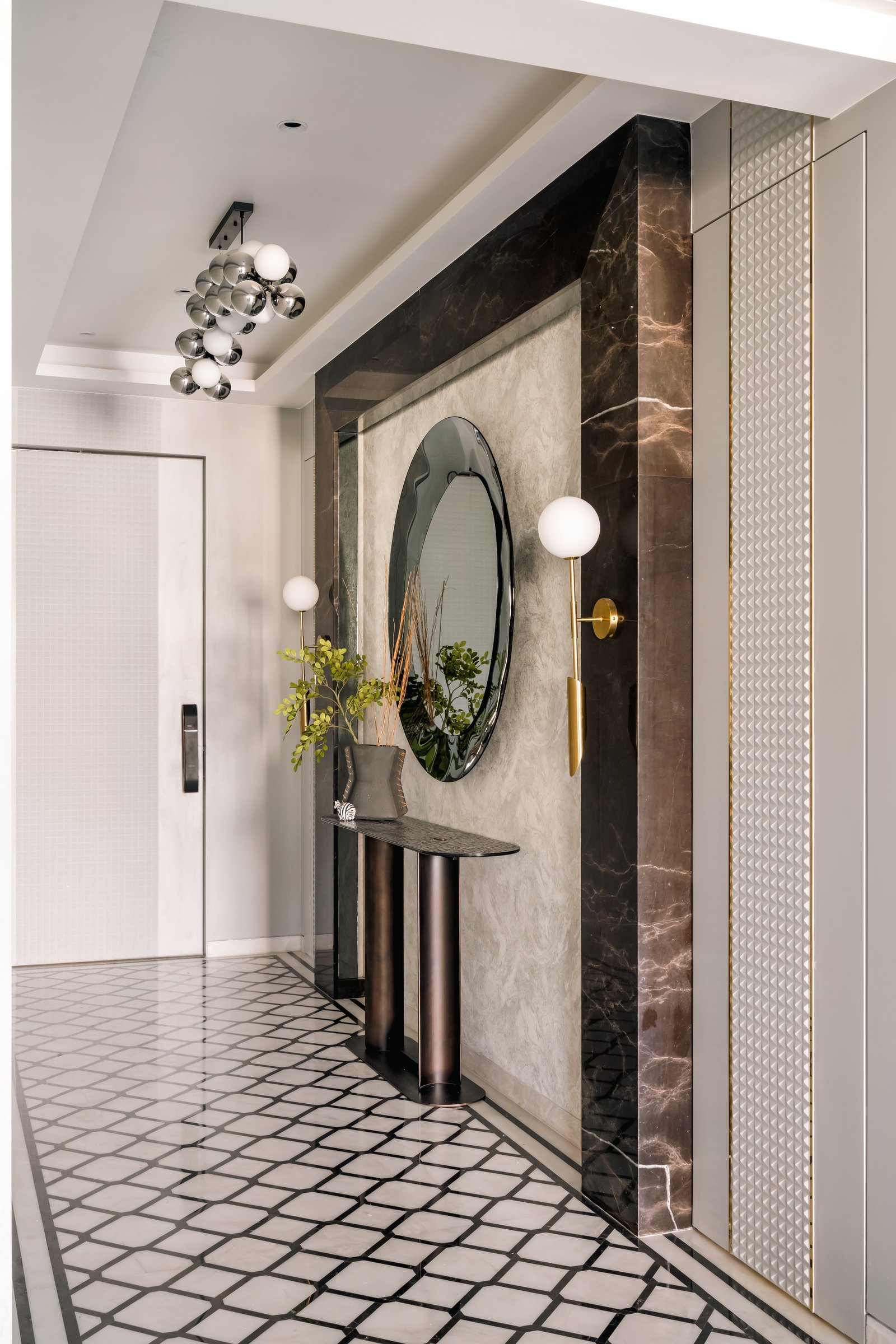 The entry foyer, where a dark stone portal and an inlaid stone floor set the home's layered grammar before the rooms reveal themselves