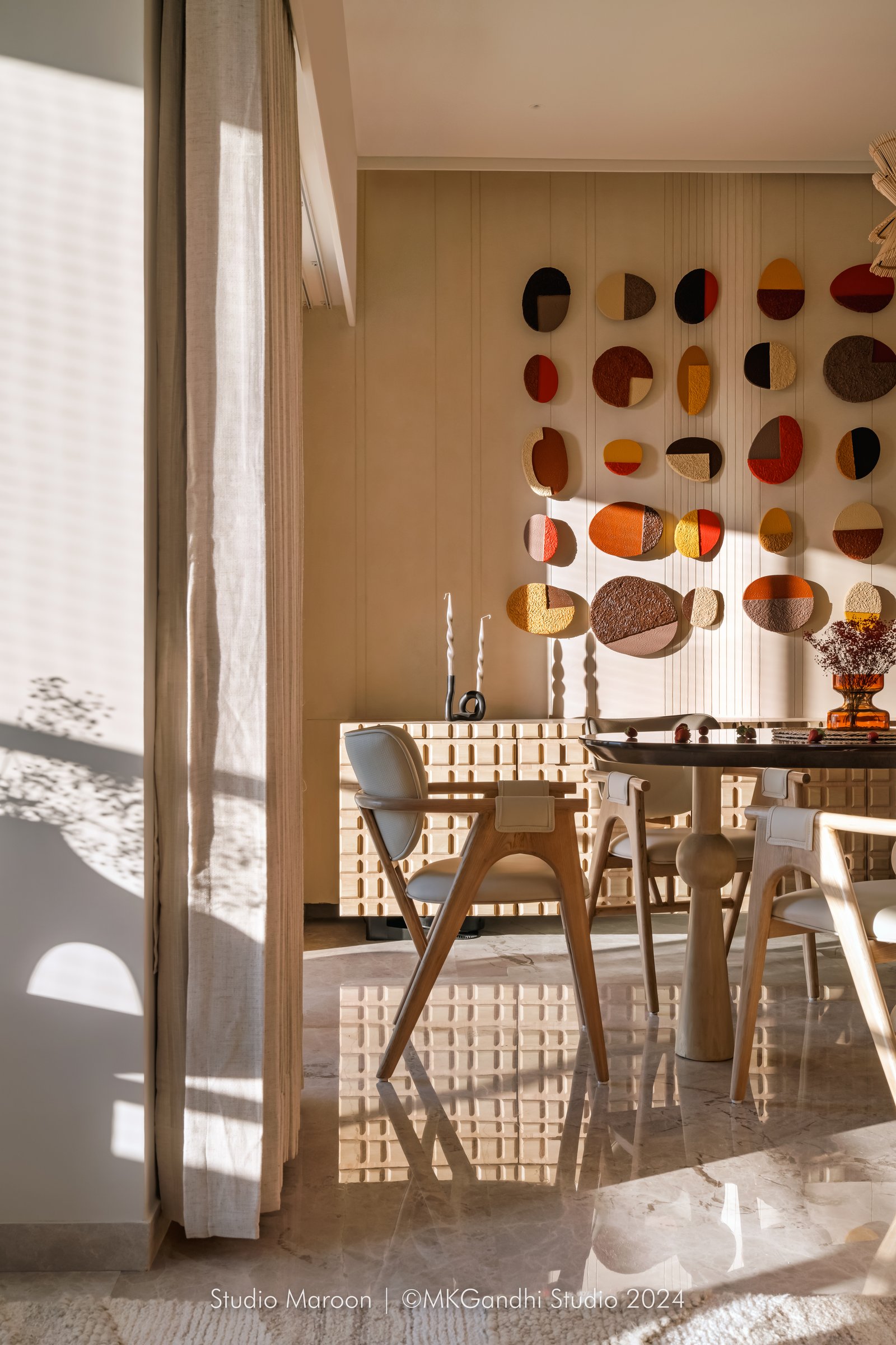Afternoon light washes over the dining zone, catching the polished stone floor and pale wood chairs