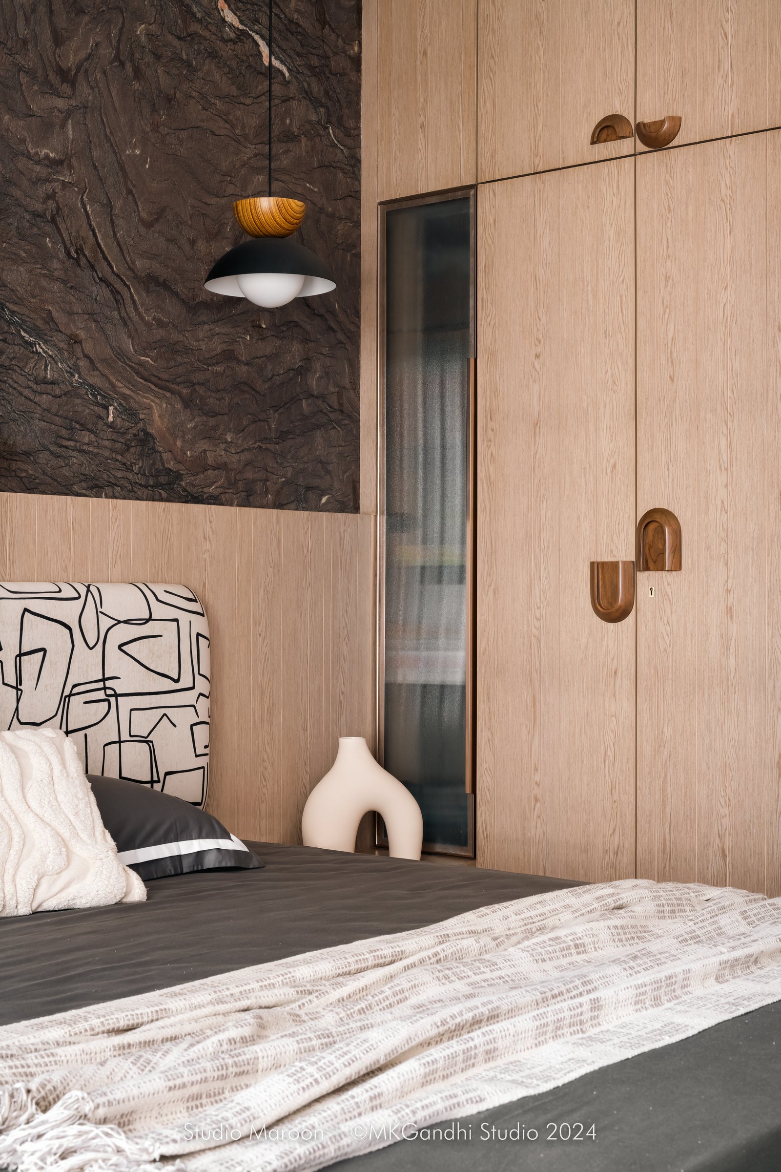 A closer view of the master bedroom, where pale wood joinery with arched pulls warms the cooler marble above