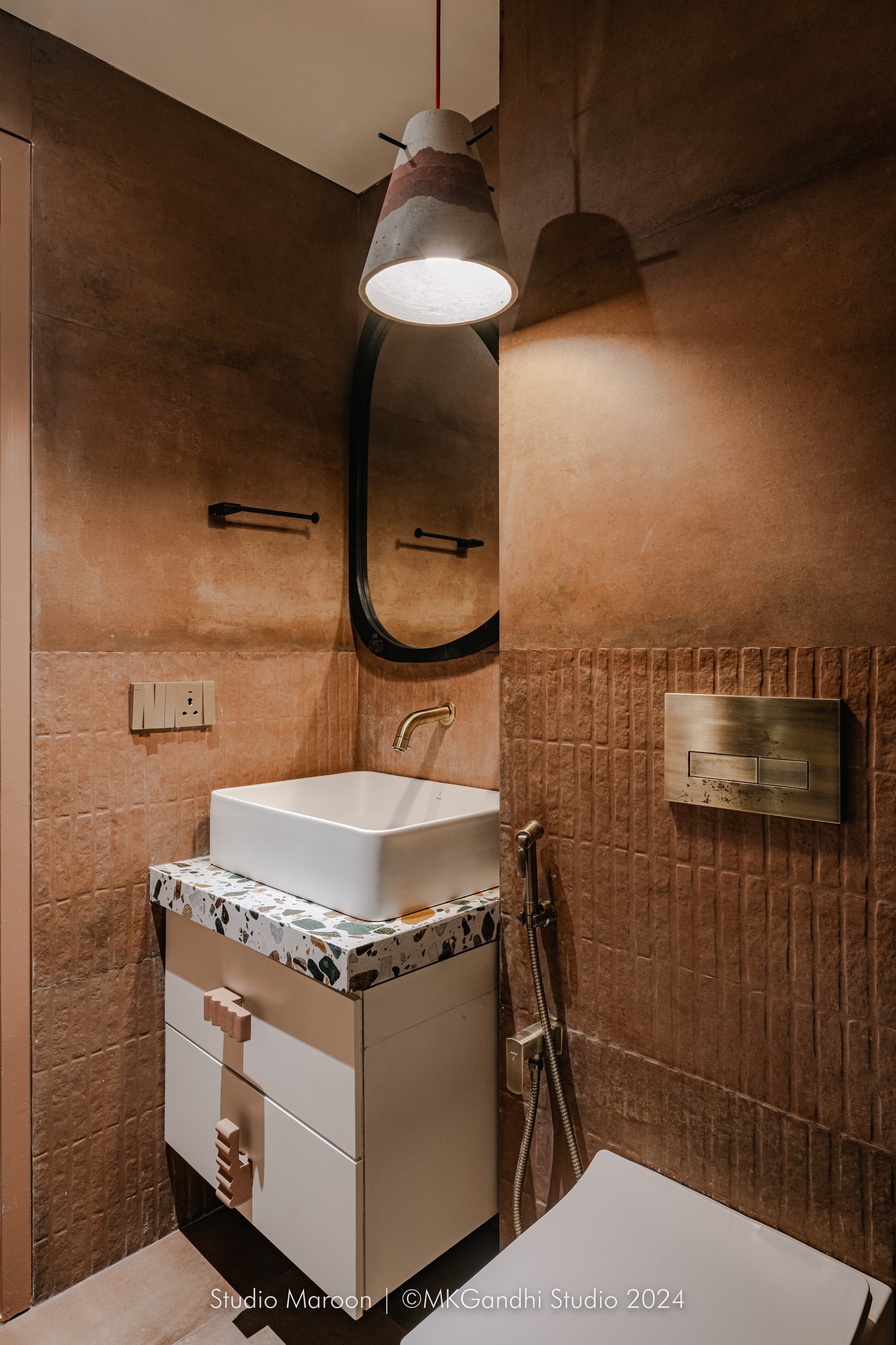 The powder room: terracotta plaster walls, ribbed dado tile, and a terrazzo vanity in jade and ochre shards