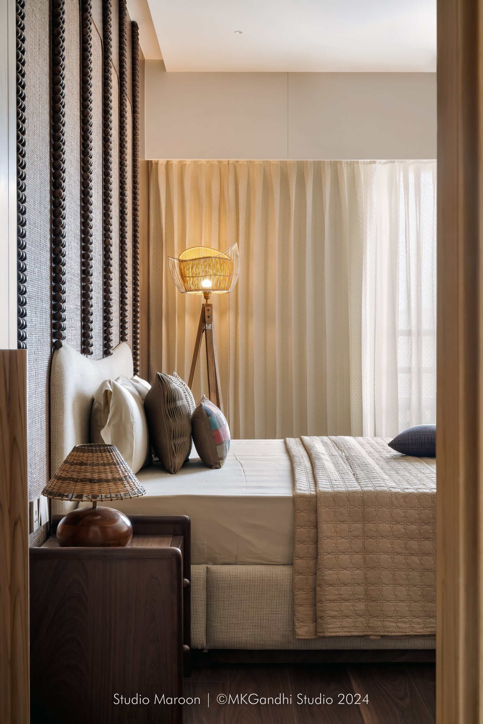 A softer view of the second bedroom, with a golden wirework lantern casting its glow across patchwork pillows