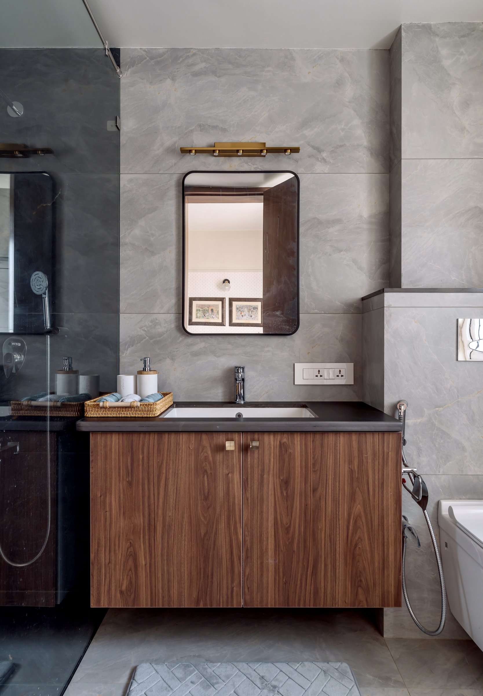 The master bathroom, where veined grey stone meets a warm walnut vanity