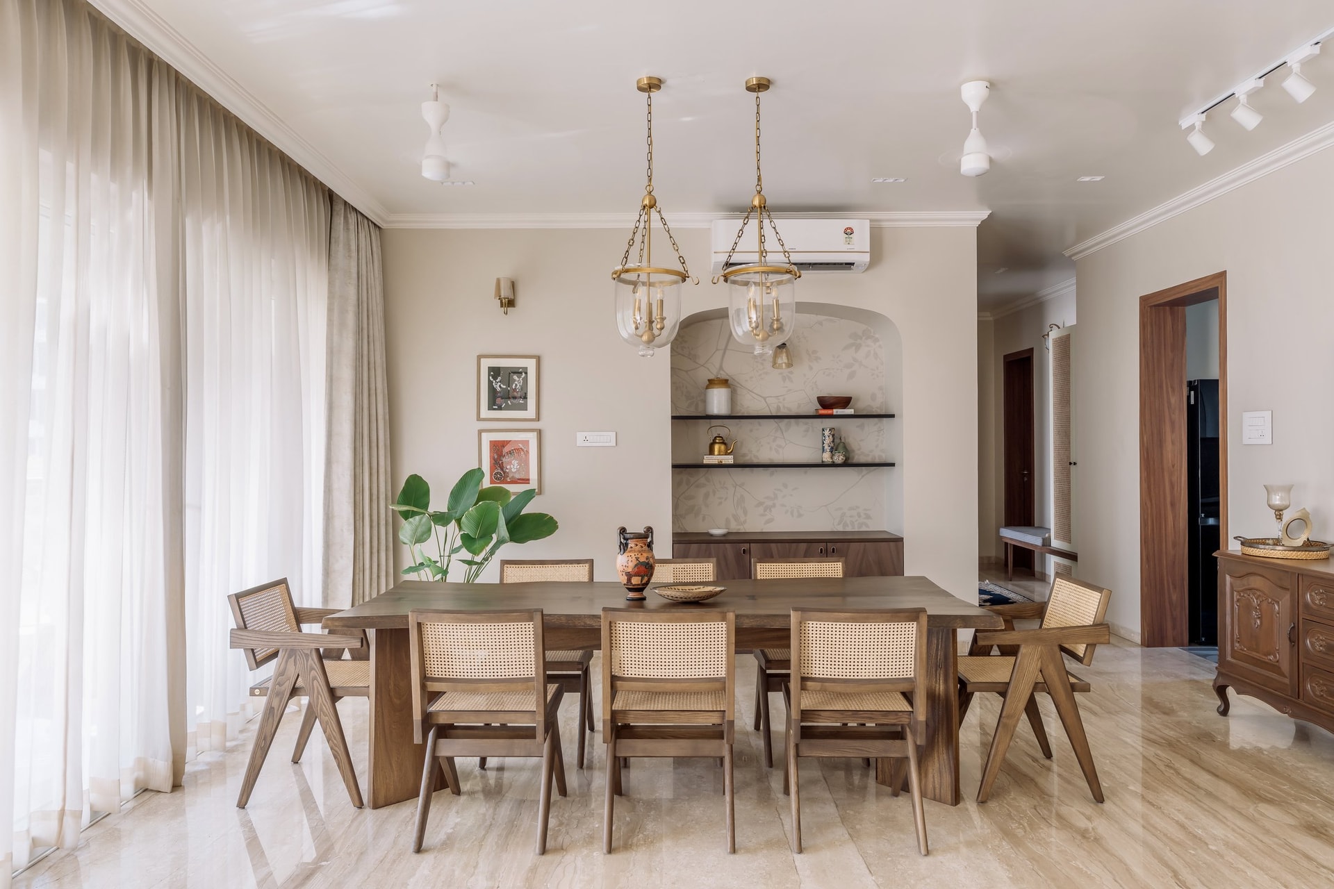 The dining room, anchored by a teak table and cane-and-wood chairs in the Chandigarh institutional language