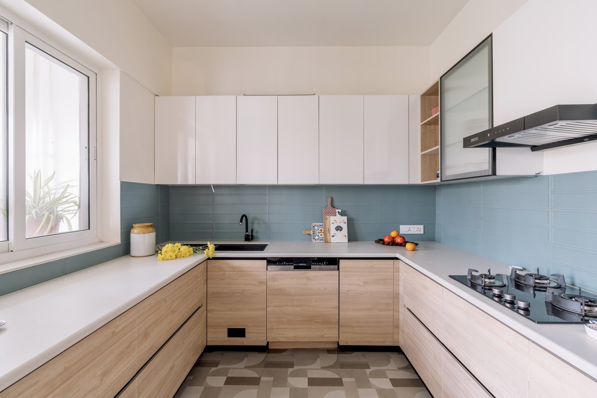 The kitchen, where a muted blue backsplash and patterned floor tiles introduce graphic calm