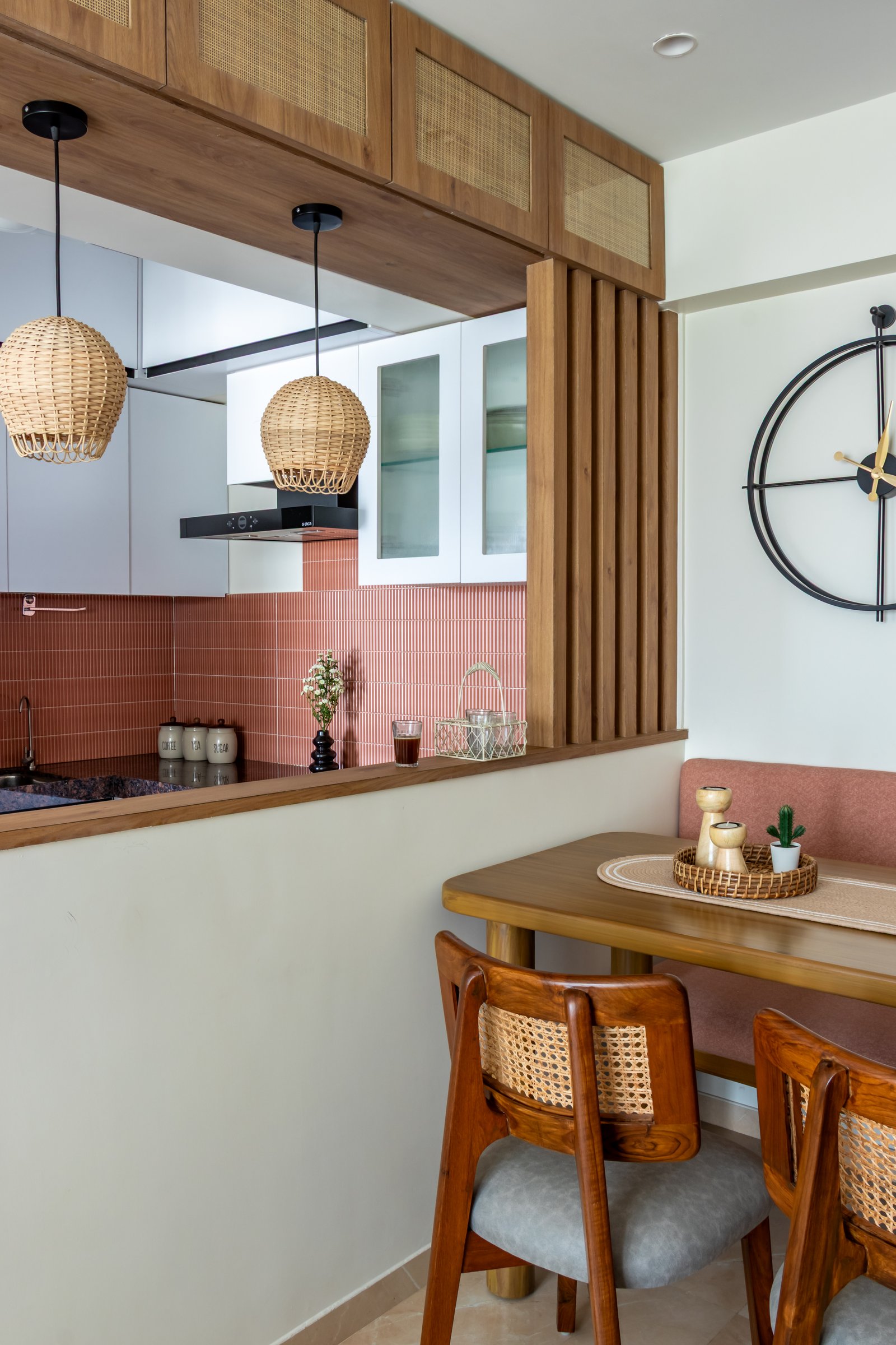 The slatted wood divider screens the kitchen without closing it off, with rattan pendants spilling light into both zones