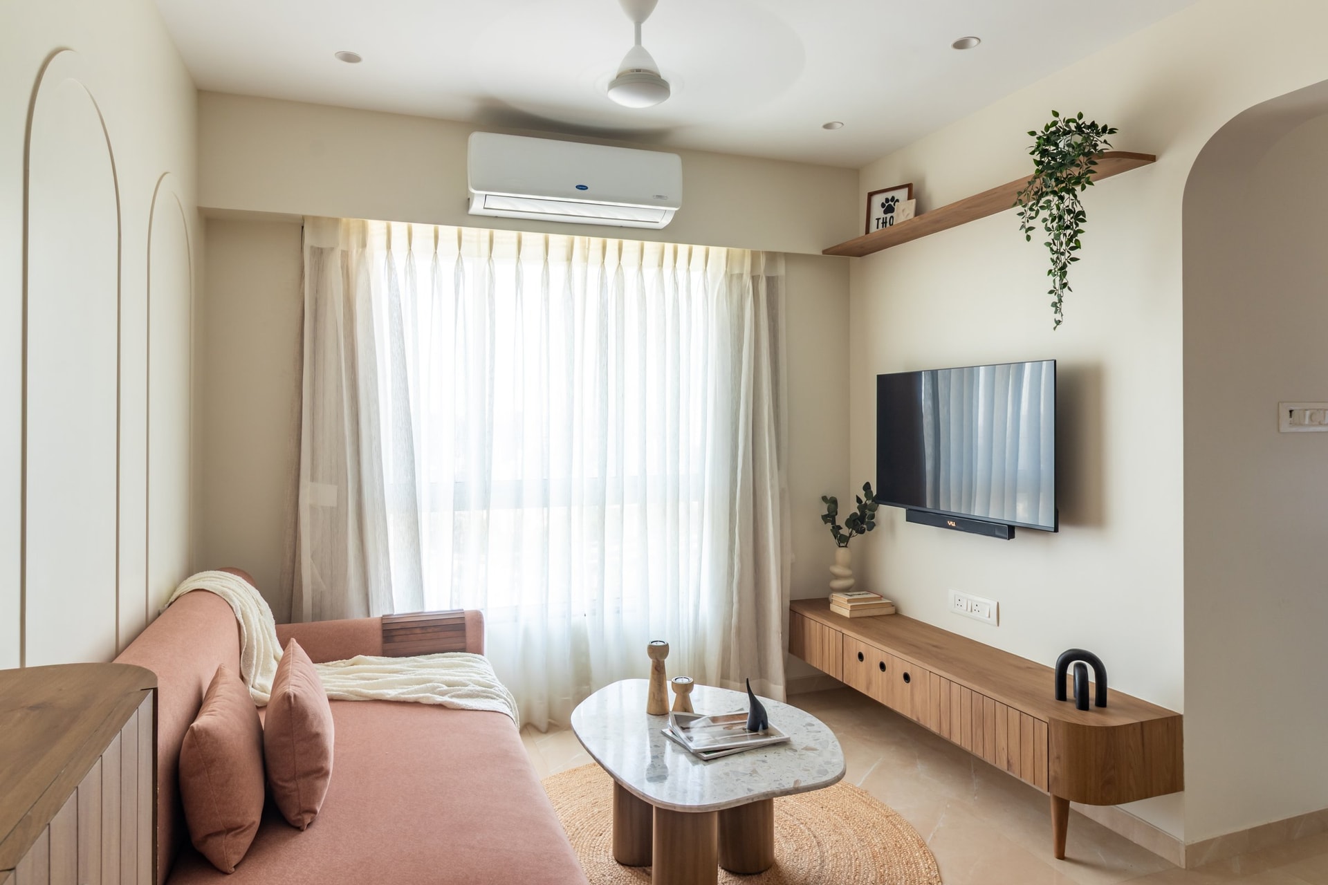 The living room, where a blush-toned sofa and floating console hold the room without crowding it