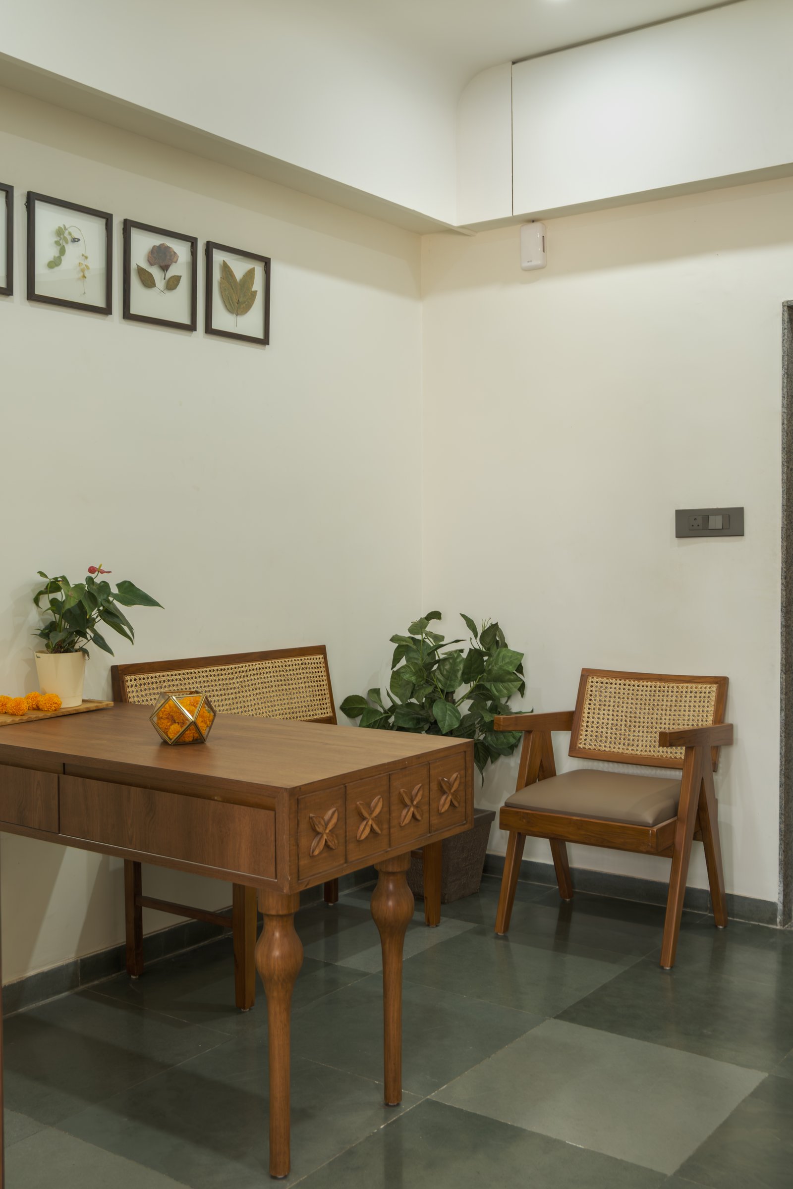The associate chamber, where a carved teak desk and cane-backed armchair sit beneath a row of framed botanical studies