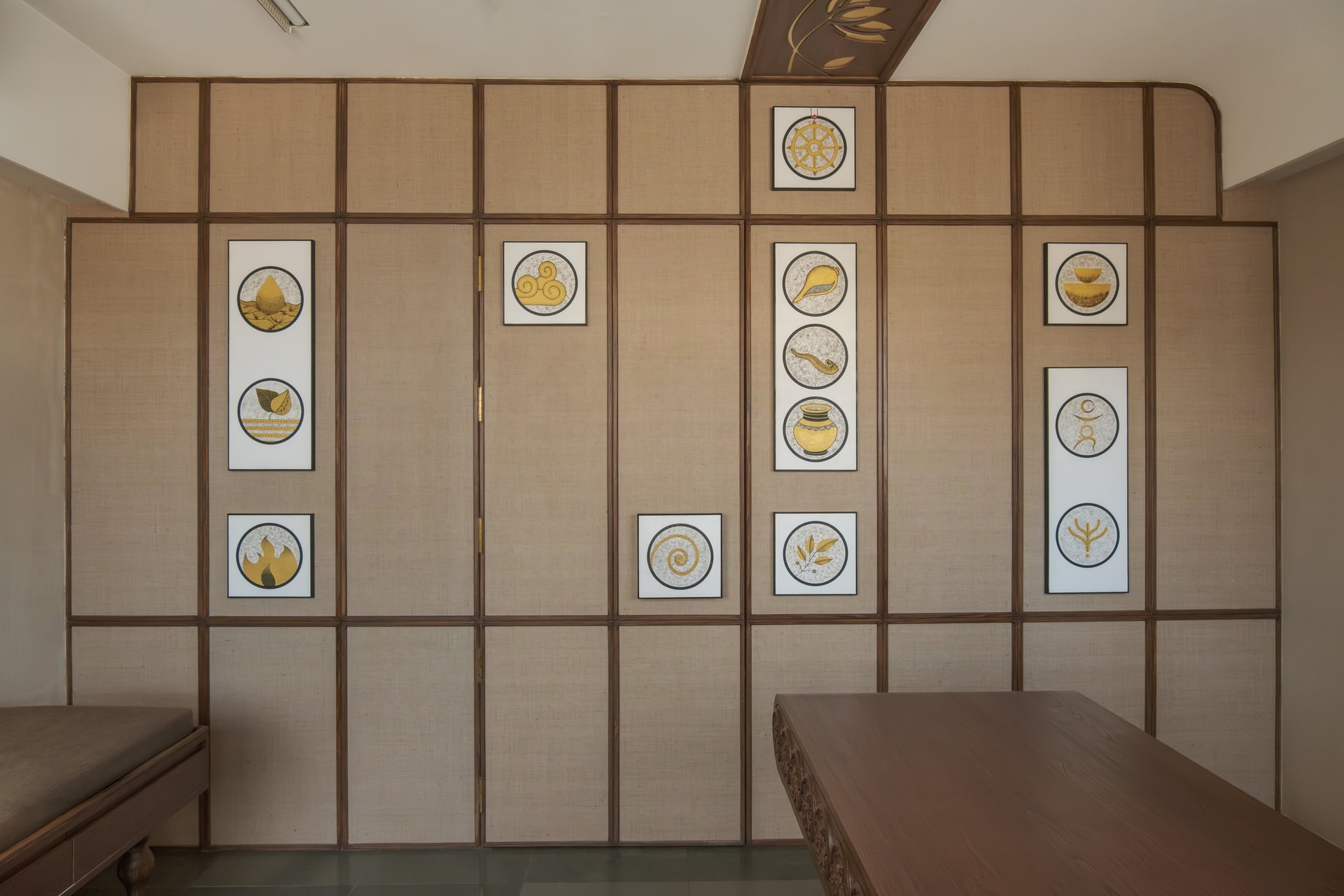 The narrative wall, where jute-clad panels framed in teak hold the Panchamahabhuta and the divine symbols of Lord Dhanvantari