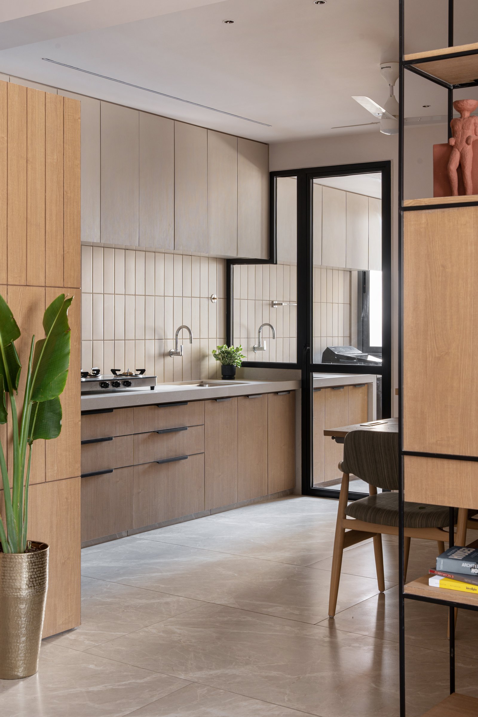 The kitchen, where wood-fronted cabinetry and a vertical tile backsplash add quiet rhythm to the working wall