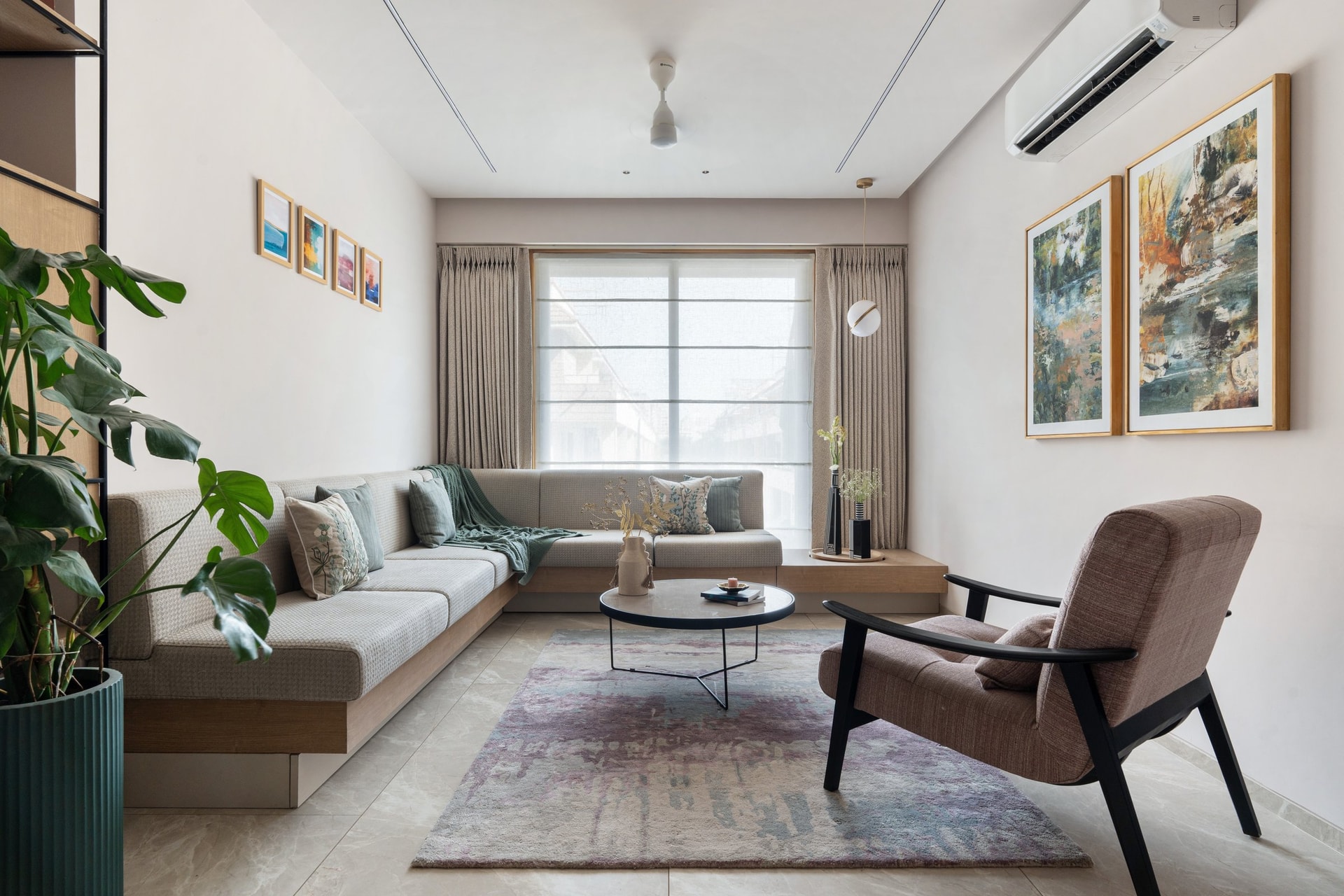 The living room, where a built-in corner sofa and a black-framed armchair balance softness with a more graphic line