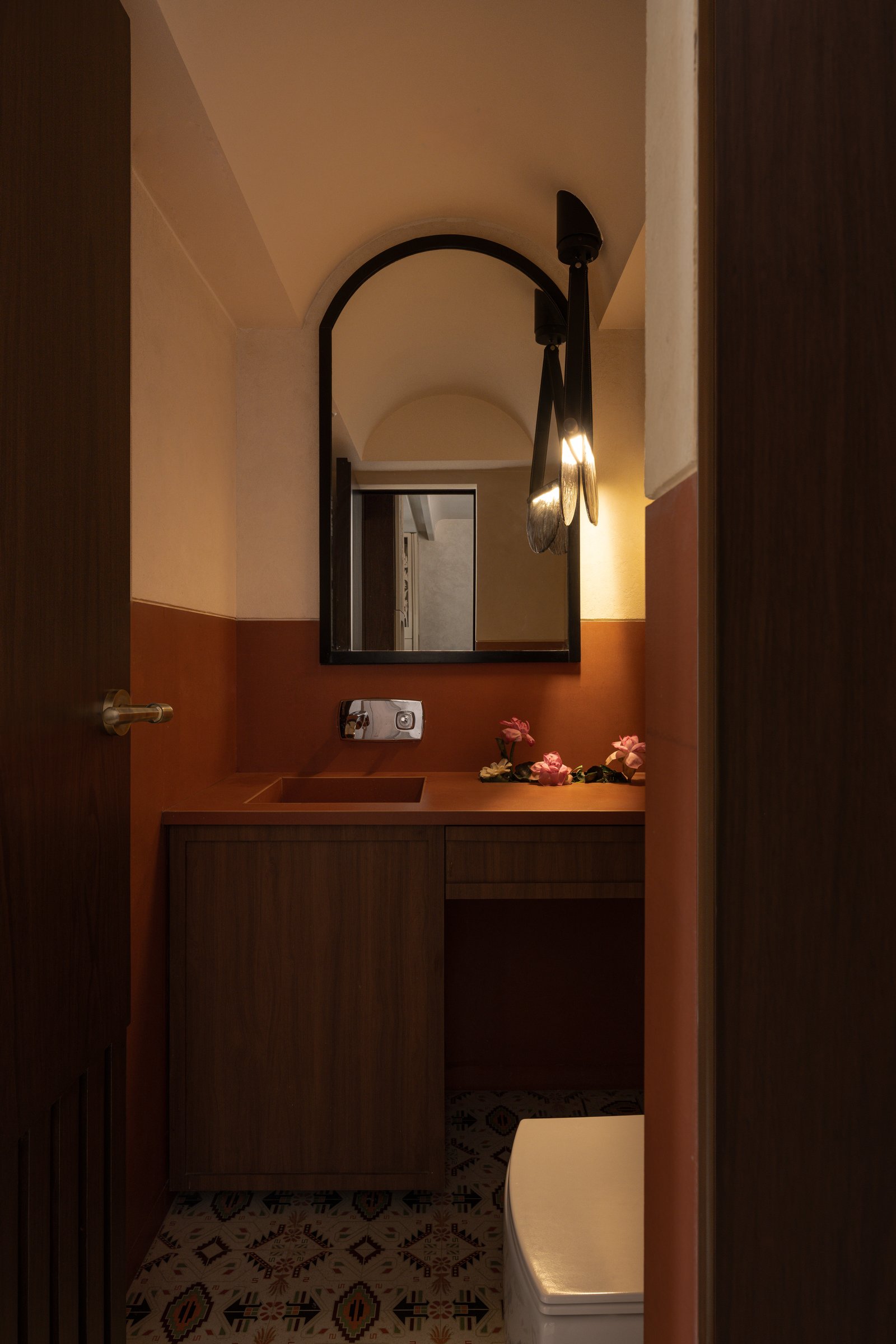 The second bathroom, where mauve tile and a sculptural fluted basin establish a quieter, denser mood