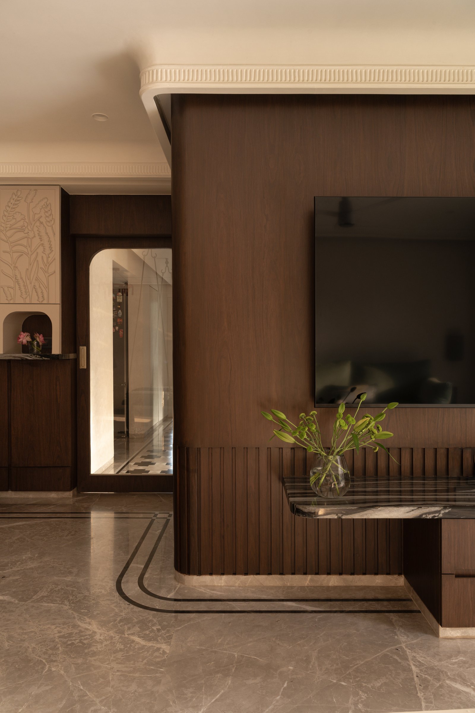 The dining and kitchen pass-through, framed by carved relief panels and a darker walnut cabinetry line