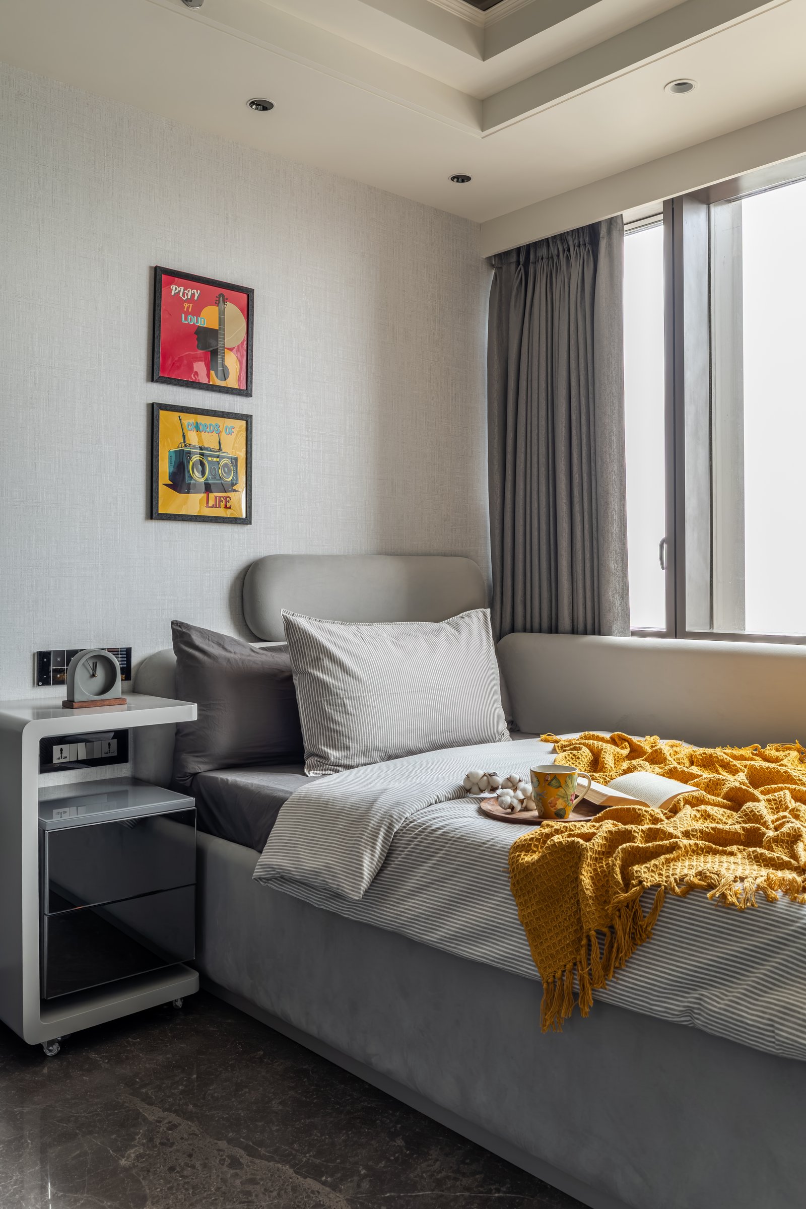 The second bedroom, where graphic pop-art prints and a mustard throw introduce the room's only chromatic notes