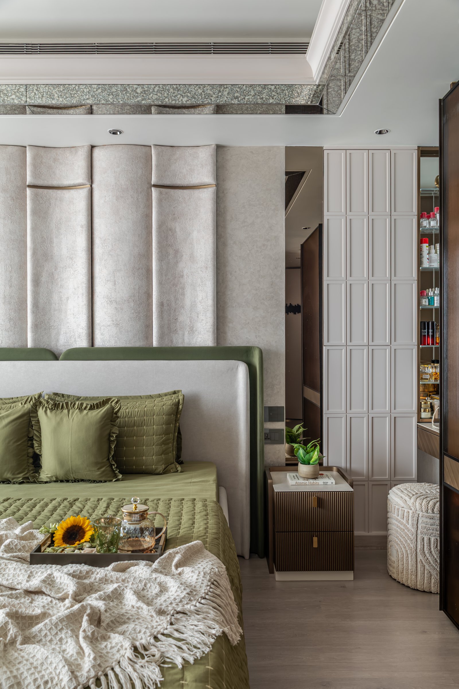 The bedroom dressing area, where a fluted cabinet system and a textured pouf maintain a warmer material register
