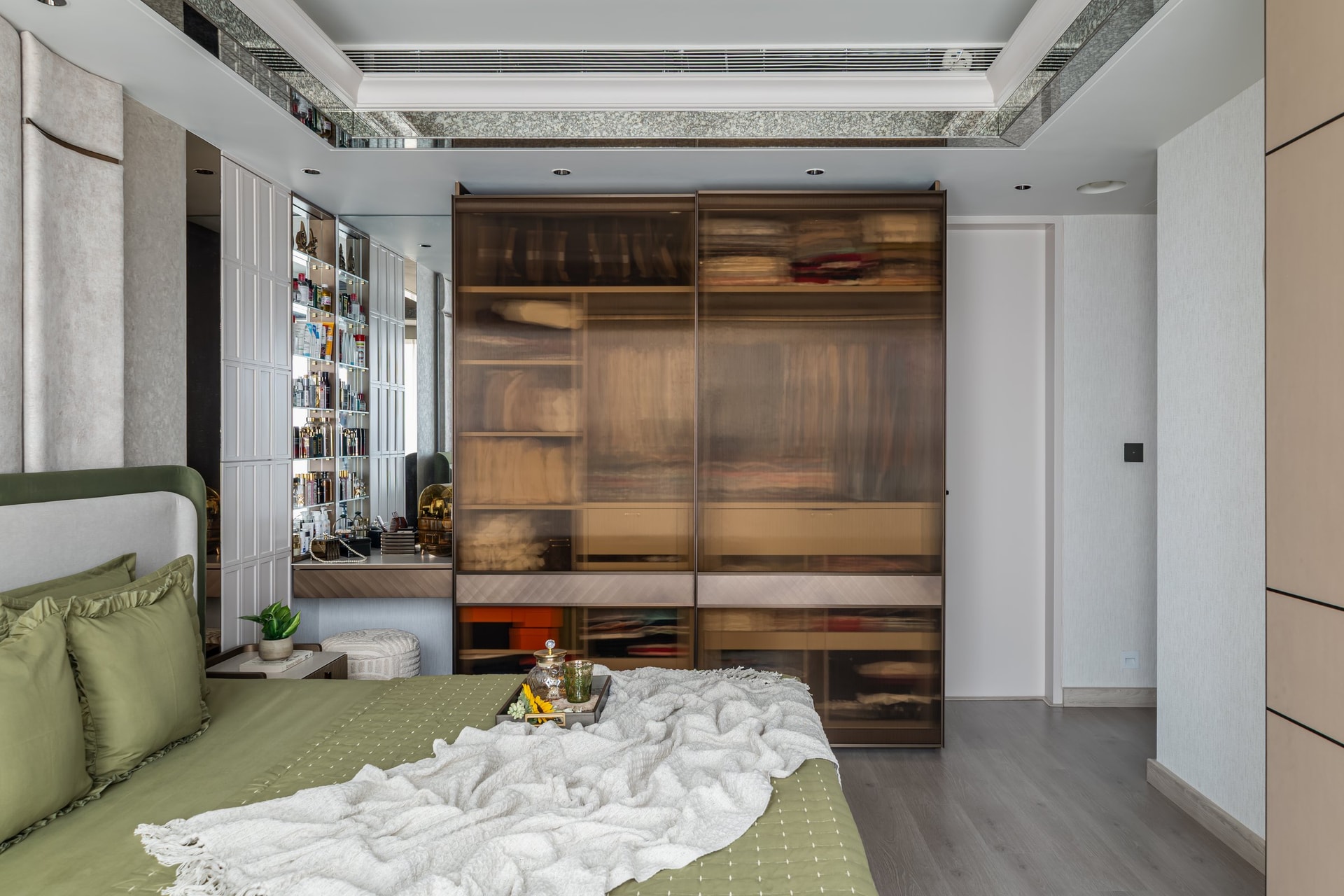 The principal suite, where a smoked bronze wardrobe lends depth to a compact plan