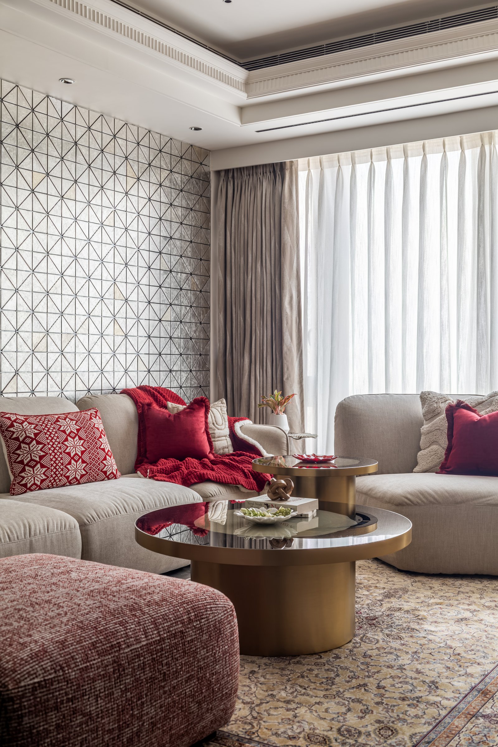 The seating arrangement, where brass-based glass tables and a hand-knotted rug ground the contemporary furniture