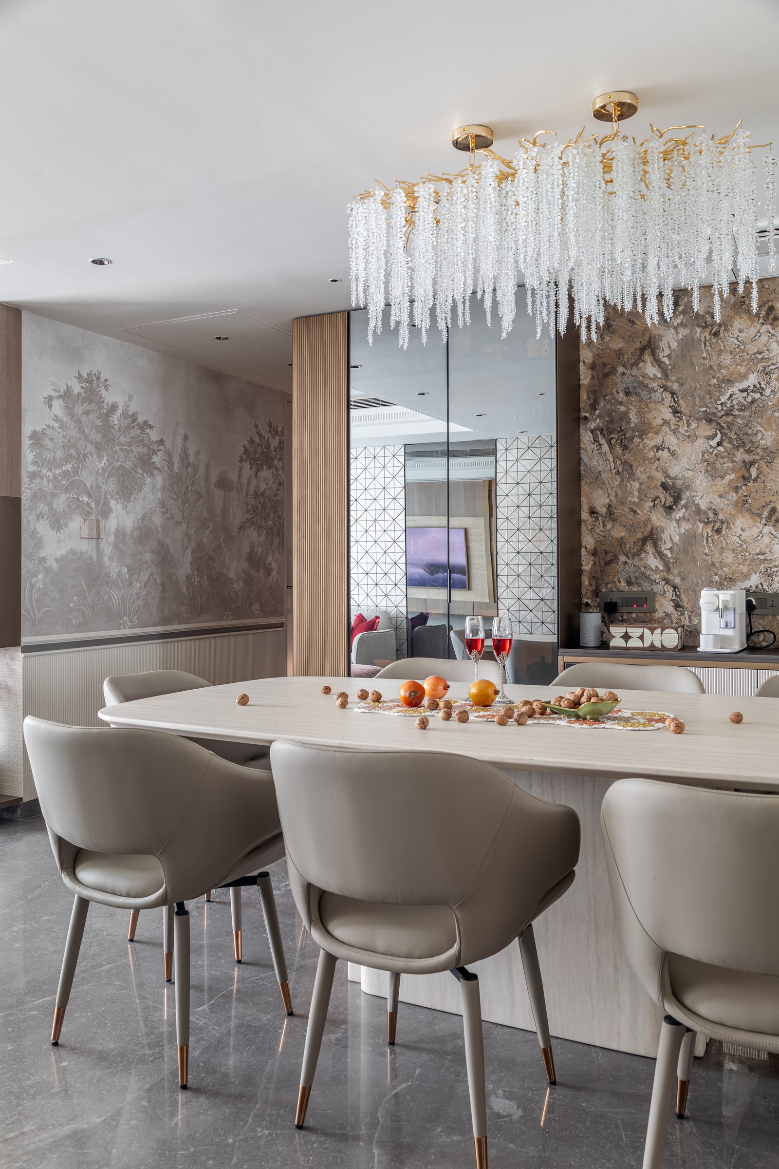 The dining room, anchored by a cascading chandelier of clear strands above an oval pale-stone table