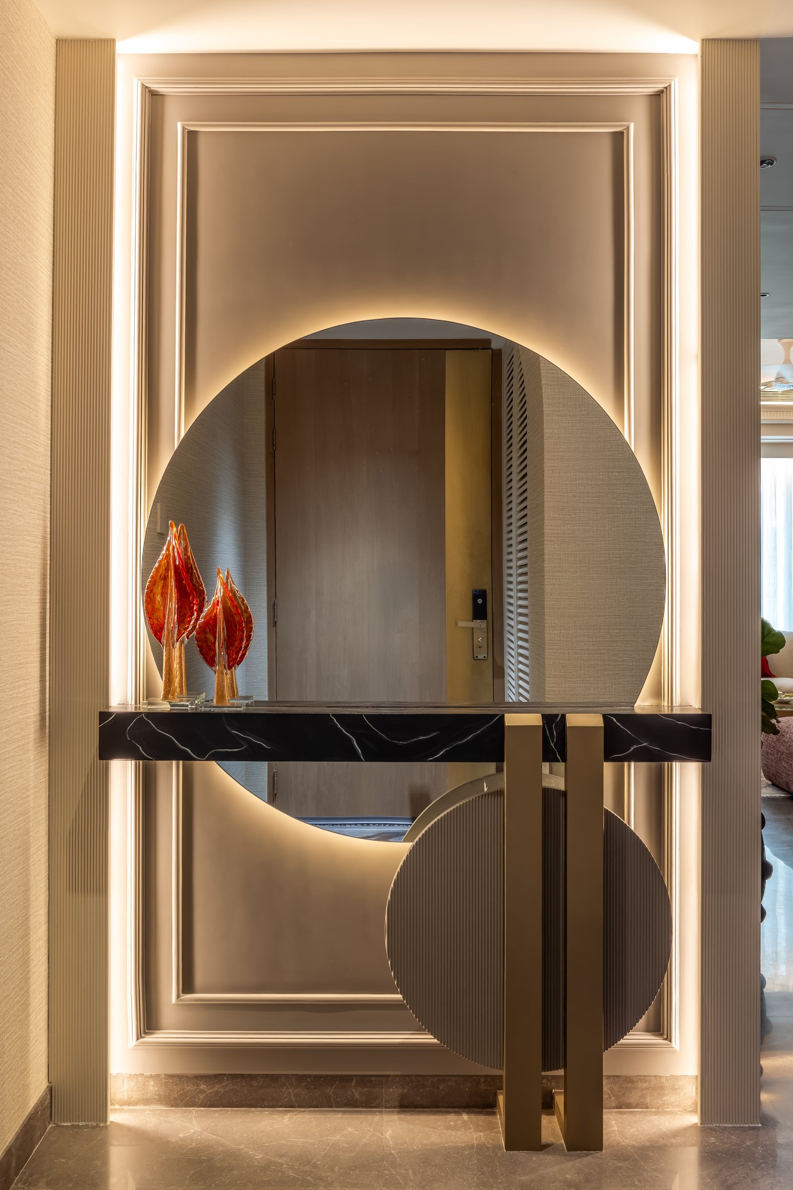 The entry, where a circular mirror, a dark-stone console, and a fluted disc establish the home's measured material register
