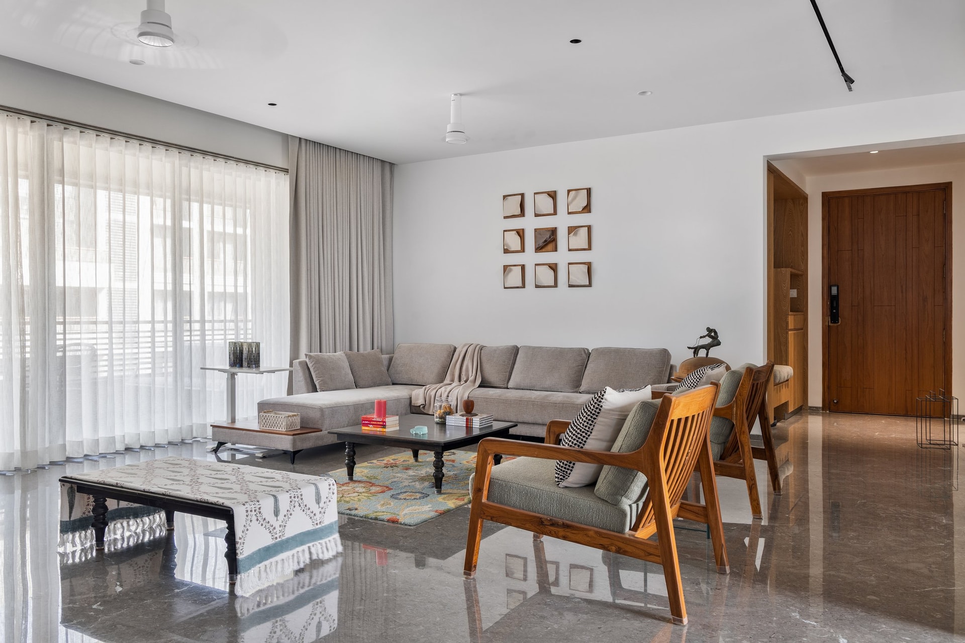 The living room, where a low grey sectional and slatted teak armchairs hold the home's neutral key