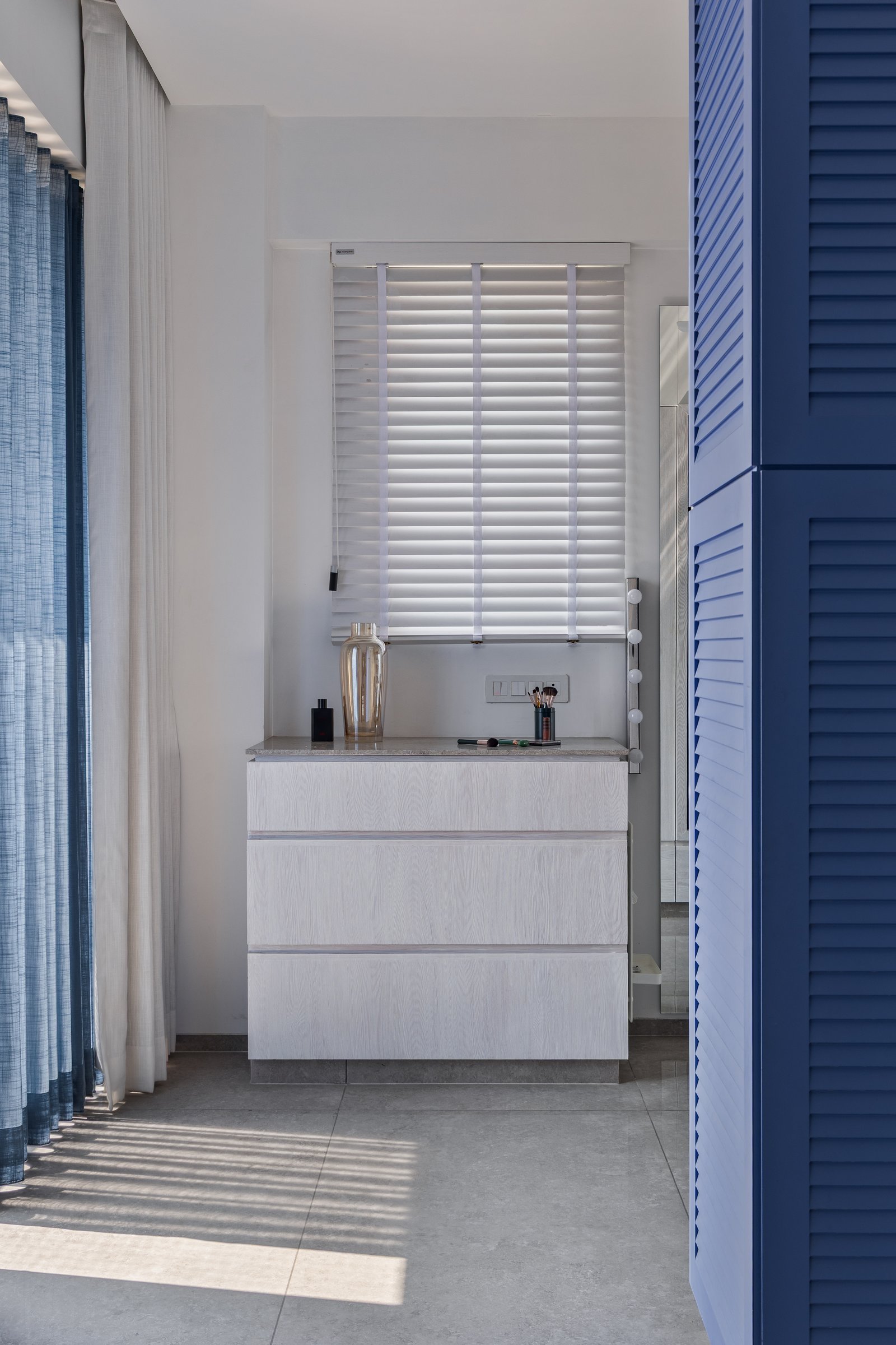 The dressing area, where the bedroom's louvered blue carries through as a connective thread