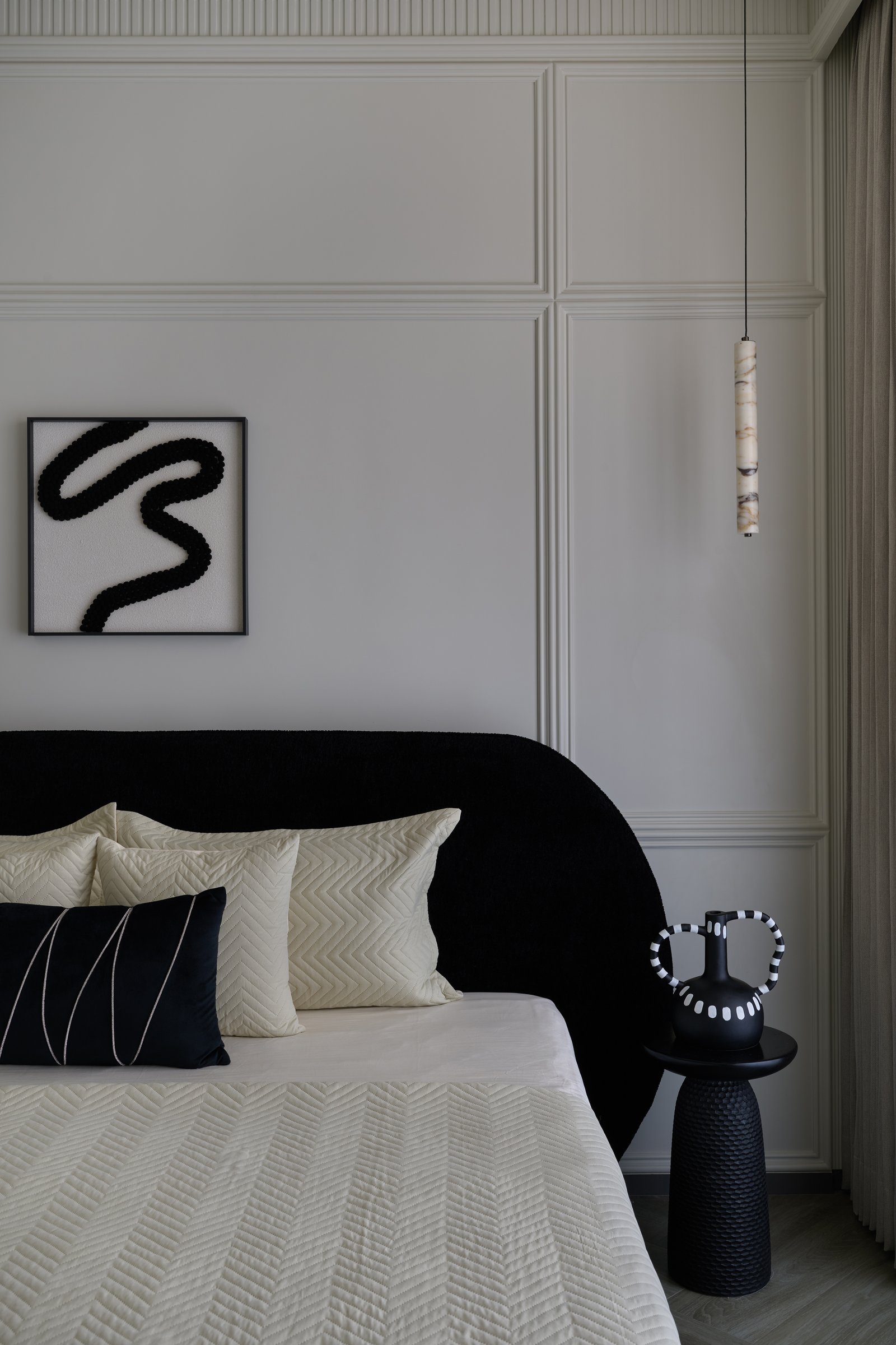 A detail of the headboard wall, where a calligraphic abstract artwork answers the curve of the headboard below