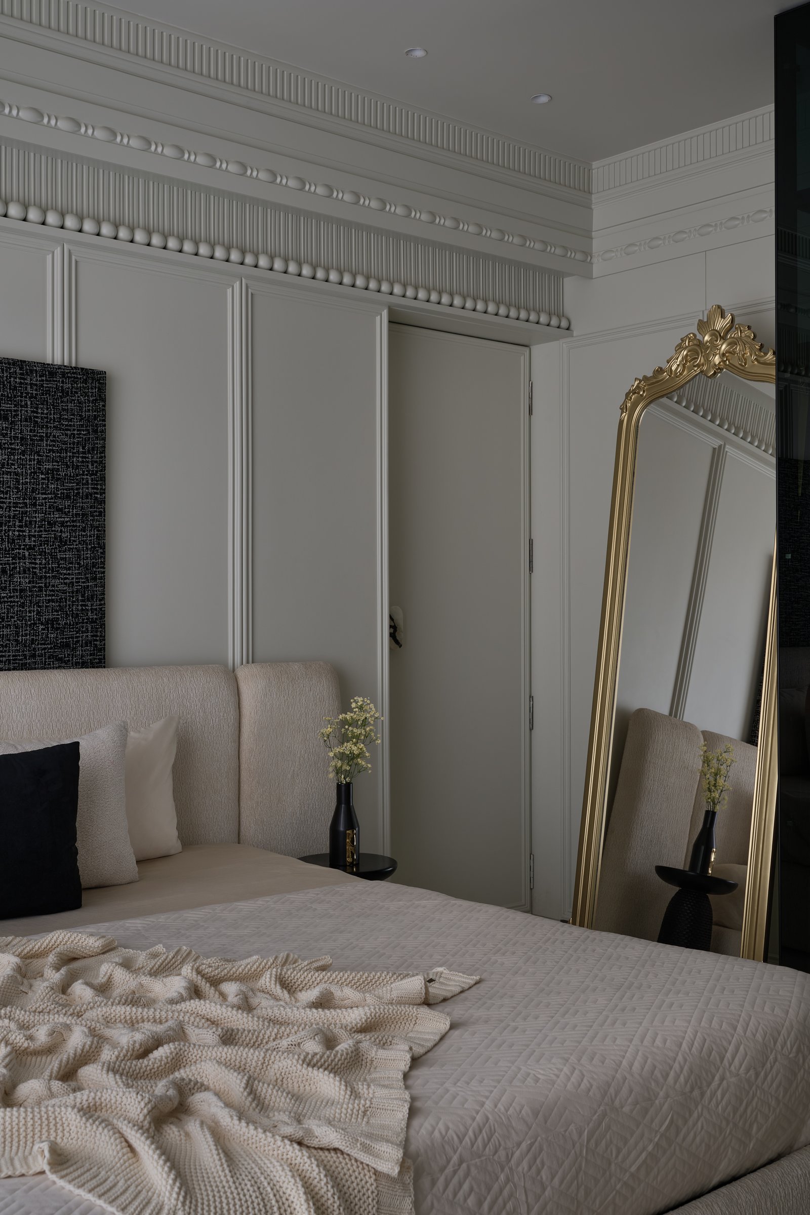 A secondary bedroom, where layered cornices and a gilded crown mirror introduce a more theatrical register