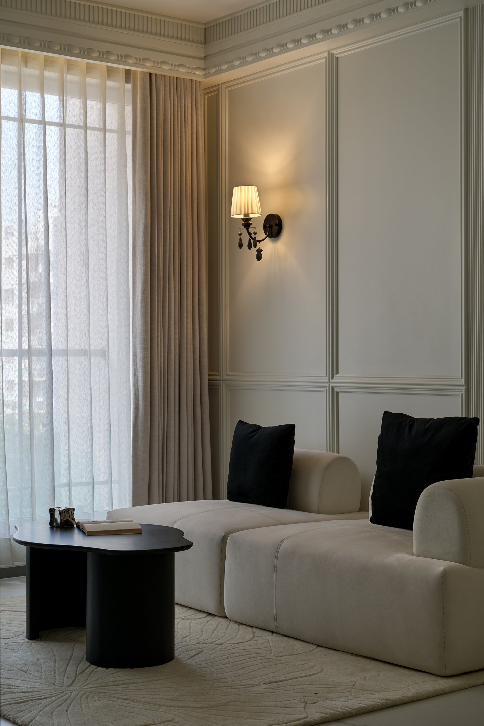 A quieter corner of the living zone, where panelled mouldings and full-height drapery carry the atmosphere
