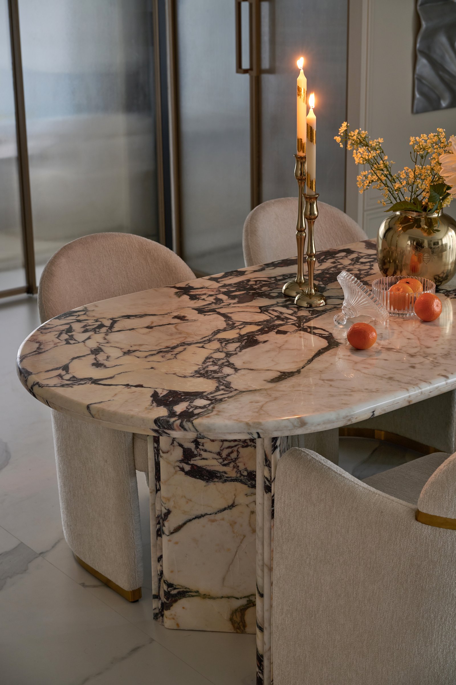 A detail of the marble table, where deep oxblood and amber veining moves through a paler ground