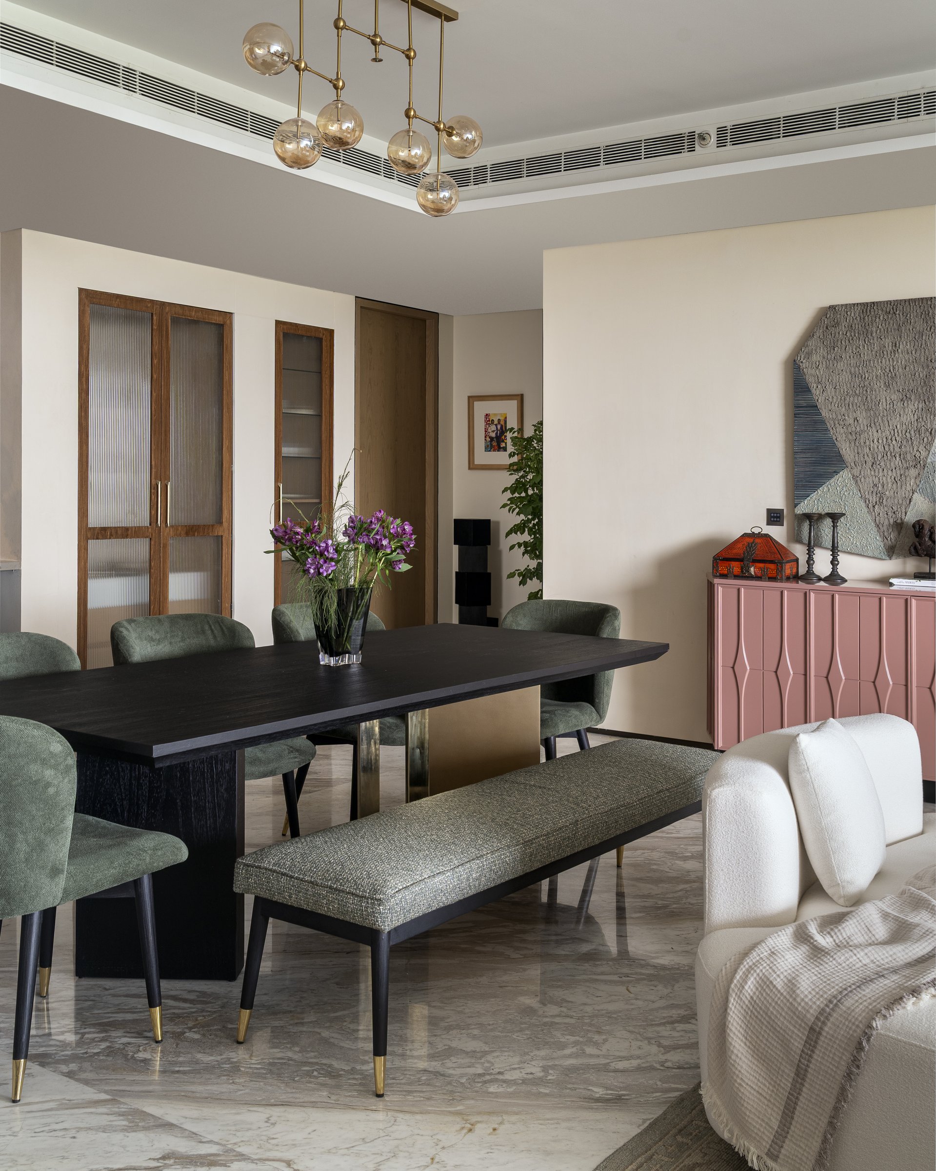 The dining area, anchored by a dusty rose sideboard and a constellation of amber glass pendants