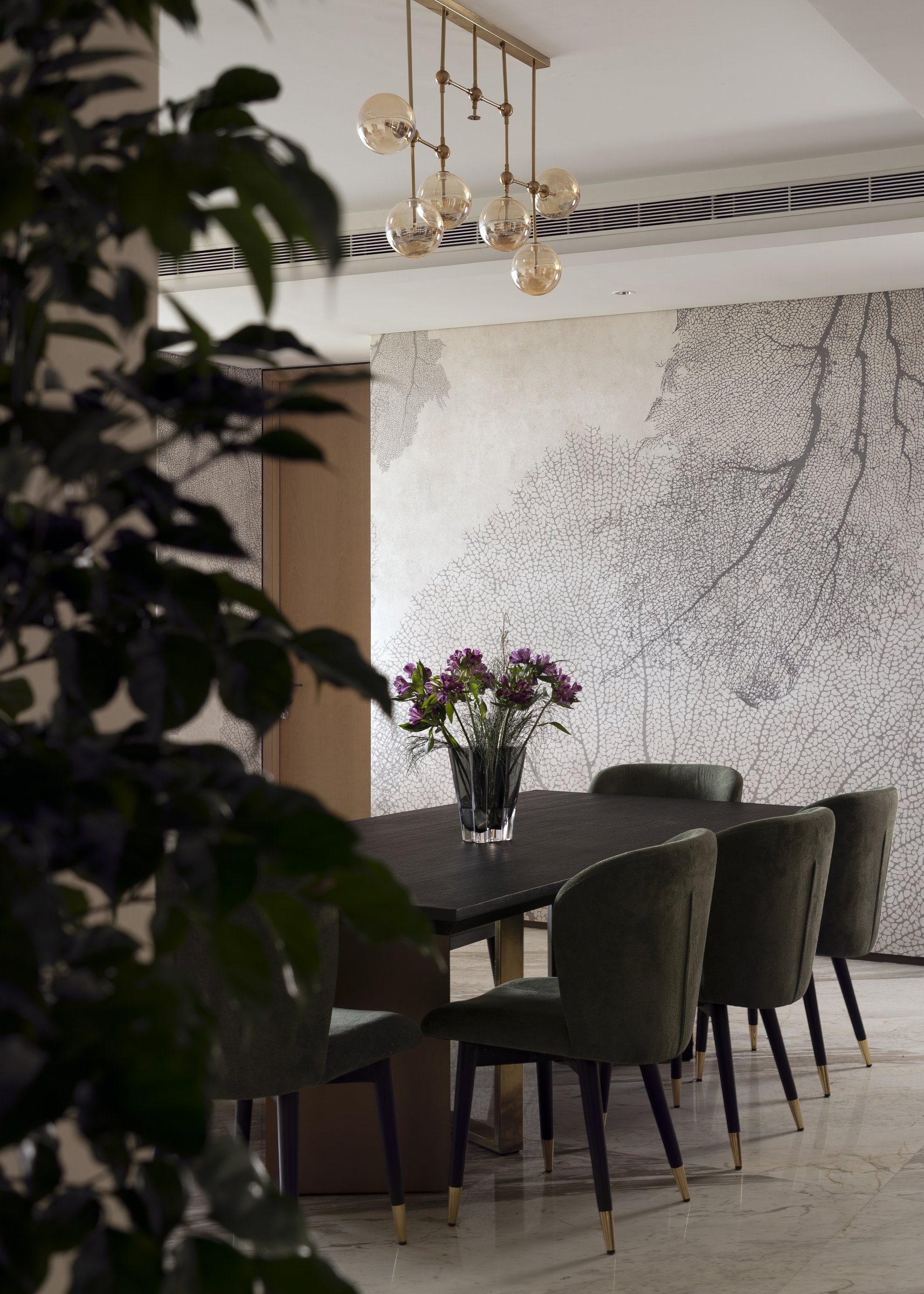 The dining table seen through foliage, the mural wall connecting it back to the living room