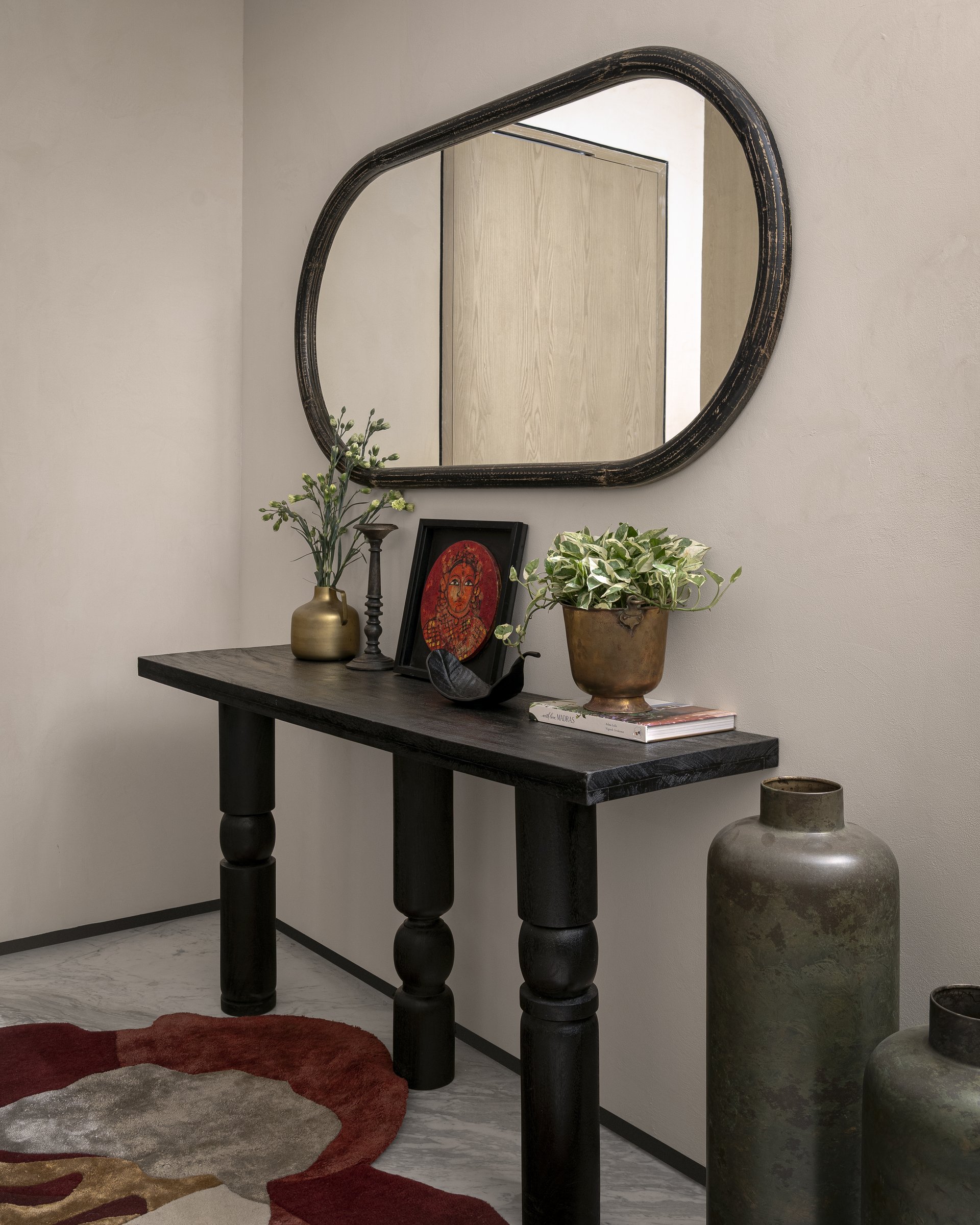 The foyer, where a turned-leg console and a generously irregular mirror set the home's appetite for collected rather than styled