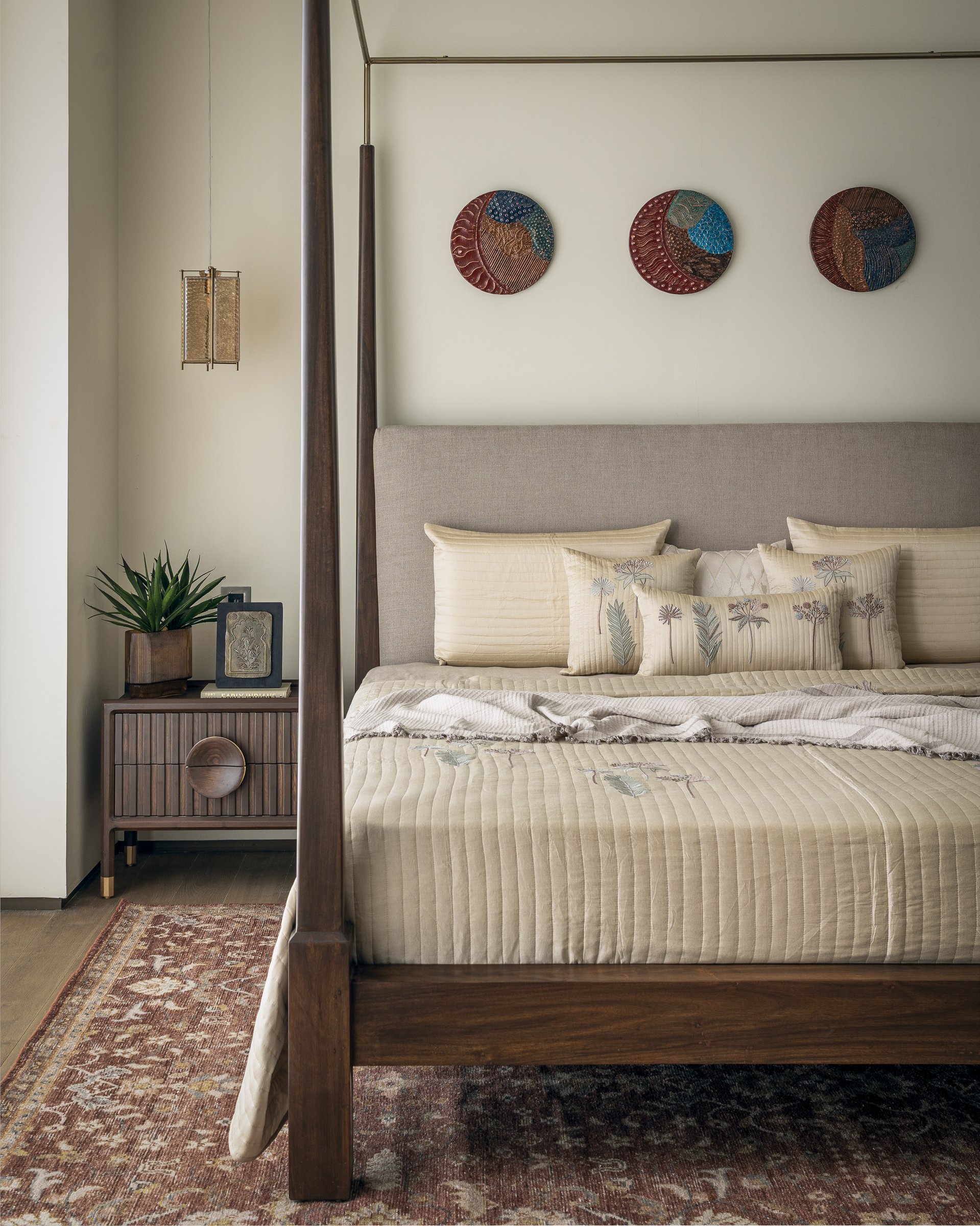A closer view of the master bed, layered in quilted linens and botanical-print cushions